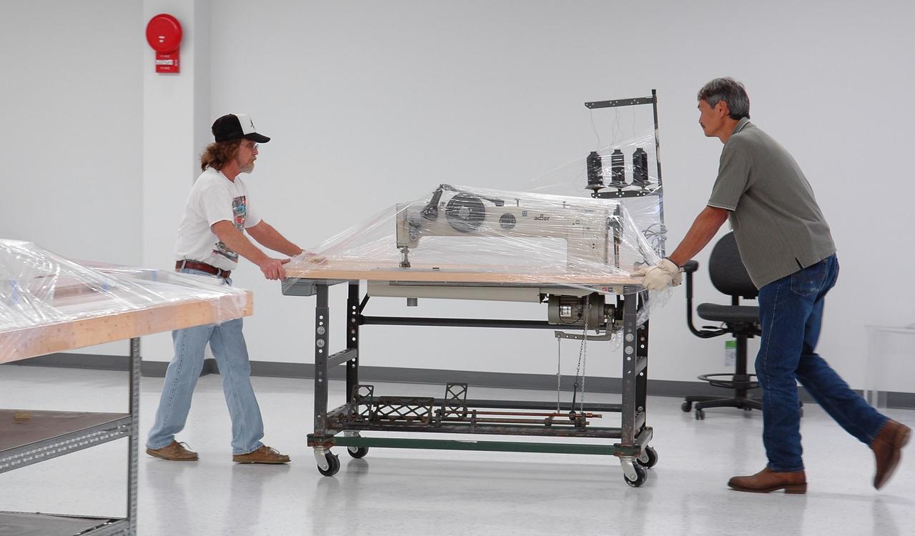 KENNEDY SPACE CENTER, FLA. - Employees at NASA Kennedy Space Center move a blanket sewing machine into the Thermal Protection System facility.   that has recently been repaired.  The upper floor of the facility, where soft material was processed, was damaged during the 2004 hurricanes and the equipment was temporarily moved to the RLV Hangar.  While the TPS facility was being repaired, normal work activity was done in the hangar.