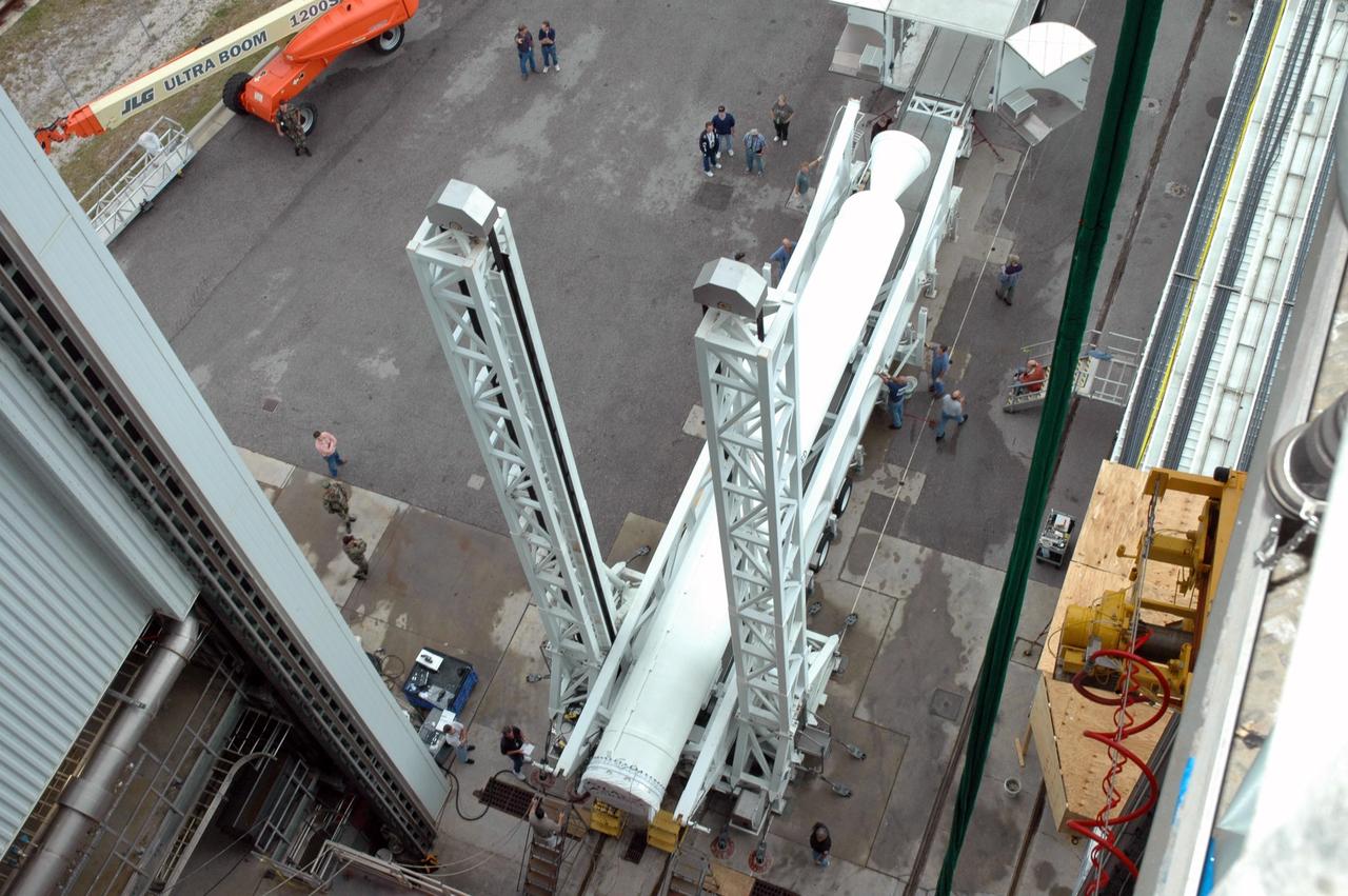 KENNEDY SPACE CENTER, FLA. - Viewed from high in the Vertical Integration Facility on Launch Complex 41 at Cape Canaveral Air Force Station in Florida, the fifth and final solid rocket booster is ready to be raised to vertical and lifted into the facility. It will be added to the other four already mated to the Lockheed Martin Atlas V rocket in the facility. The Atlas V is the launch vehicle for the Pluto-bound New Horizons spacecraft that will make the first reconnaissance of Pluto and its moon, Charon - a "double planet" and the last planet in our solar system to be visited by spacecraft. As it approaches Pluto, the spacecraft will look for ultraviolet emission from Pluto's atmosphere and make the best global maps of Pluto and Charon in green, blue, red and a special wavelength that is sensitive to methane frost on the surface. It will also take spectral maps in the near infrared, telling the science team about Pluto's and Charon’s surface compositions and locations and temperatures of these materials. When the spacecraft is closest to Pluto or its moon, it will take close-up pictures in both visible and near-infrared wavelengths. The mission will then visit one or more objects in the Kuiper Belt region beyond Neptune. New Horizons is scheduled to launch in January 2006, swing past Jupiter for a gravity boost and scientific studies in February or March 2007, and reach Pluto and Charon in July 2015.