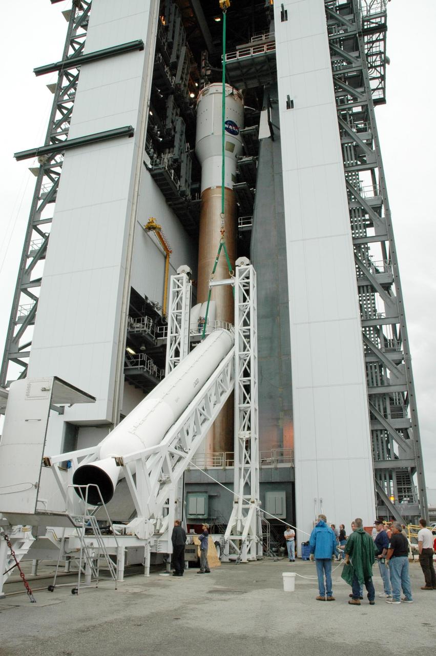 KENNEDY SPACE CENTER, FLA. - On Launch Complex 41 at Cape Canaveral Air Force Station in Florida, the fifth and final solid rocket booster is being raised to a vertical position. It will be lifted and added to the other four already mated to the Lockheed Martin Atlas V rocket in the Vertical Integration Facility. The Atlas V is the launch vehicle for the Pluto-bound New Horizons spacecraft that will make the first reconnaissance of Pluto and its moon, Charon - a "double planet" and the last planet in our solar system to be visited by spacecraft. As it approaches Pluto, the spacecraft will look for ultraviolet emission from Pluto's atmosphere and make the best global maps of Pluto and Charon in green, blue, red and a special wavelength that is sensitive to methane frost on the surface. It will also take spectral maps in the near infrared, telling the science team about Pluto's and Charon’s surface compositions and locations and temperatures of these materials. When the spacecraft is closest to Pluto or its moon, it will take close-up pictures in both visible and near-infrared wavelengths. The mission will then visit one or more objects in the Kuiper Belt region beyond Neptune. New Horizons is scheduled to launch in January 2006, swing past Jupiter for a gravity boost and scientific studies in February or March 2007, and reach Pluto and Charon in July 2015.