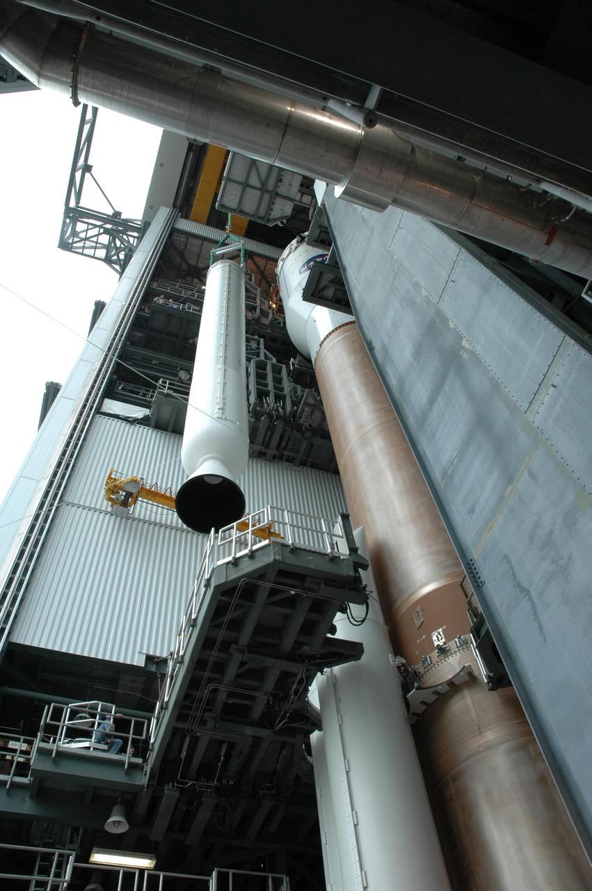 KENNEDY SPACE CENTER, FLA. - On Launch Complex 41 at Cape Canaveral Air Force Station in Florida, the fifth and final solid rocket booster is being lifted into the Vertical Integration Facility. It will be added to the other four already mated to the Lockheed Martin Atlas V rocket there. The Atlas V is the launch vehicle for the Pluto-bound New Horizons spacecraft that will make the first reconnaissance of Pluto and its moon, Charon - a "double planet" and the last planet in our solar system to be visited by spacecraft. As it approaches Pluto, the spacecraft will look for ultraviolet emission from Pluto's atmosphere and make the best global maps of Pluto and Charon in green, blue, red and a special wavelength that is sensitive to methane frost on the surface. It will also take spectral maps in the near infrared, telling the science team about Pluto's and Charon’s surface compositions and locations and temperatures of these materials. When the spacecraft is closest to Pluto or its moon, it will take close-up pictures in both visible and near-infrared wavelengths. The mission will then visit one or more objects in the Kuiper Belt region beyond Neptune. New Horizons is scheduled to launch in January 2006, swing past Jupiter for a gravity boost and scientific studies in February or March 2007, and reach Pluto and Charon in July 2015.