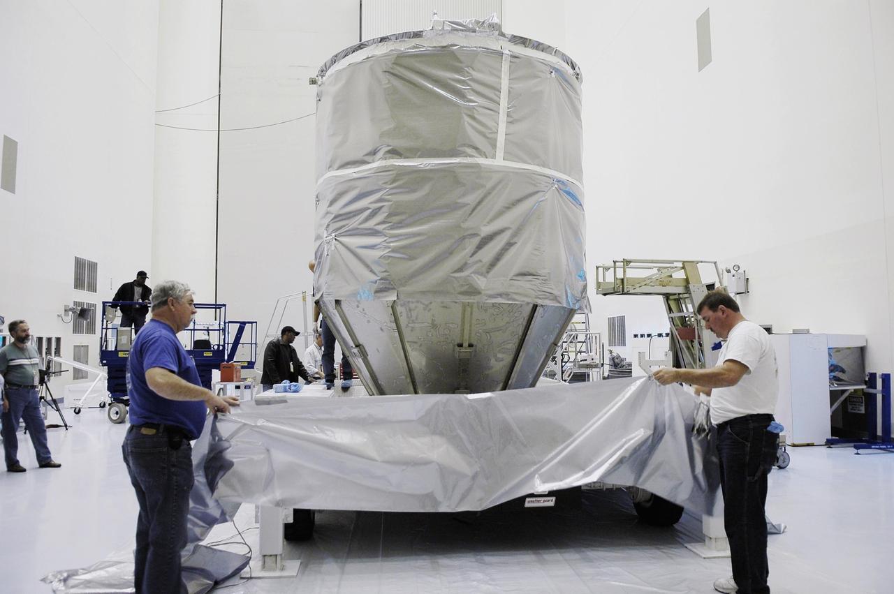 KENNEDY SPACE CENTER, FLA. -   Inside NASA Kennedy Space Center’s Payload Hazardous Servicing Facility, workers remove the protective cover from around the newly arrived third stage, or upper stage for the New Horizons spacecraft.  The third stage is  a Boeing STAR 48 solid-propellant kick motor.  The Atlas V is the launch vehicle for NASA’s New Horizons spacecraft, scheduled to launch from Cape Canaveral Air Force Station, Fla., during a 35-day window that opens Jan. 11 and fly through the Pluto system as early as summer 2015. New Horizons will be powered by a single radioisotope thermoelectric generator (RTG), provided by the Department of Energy, which will be installed shortly before launch.