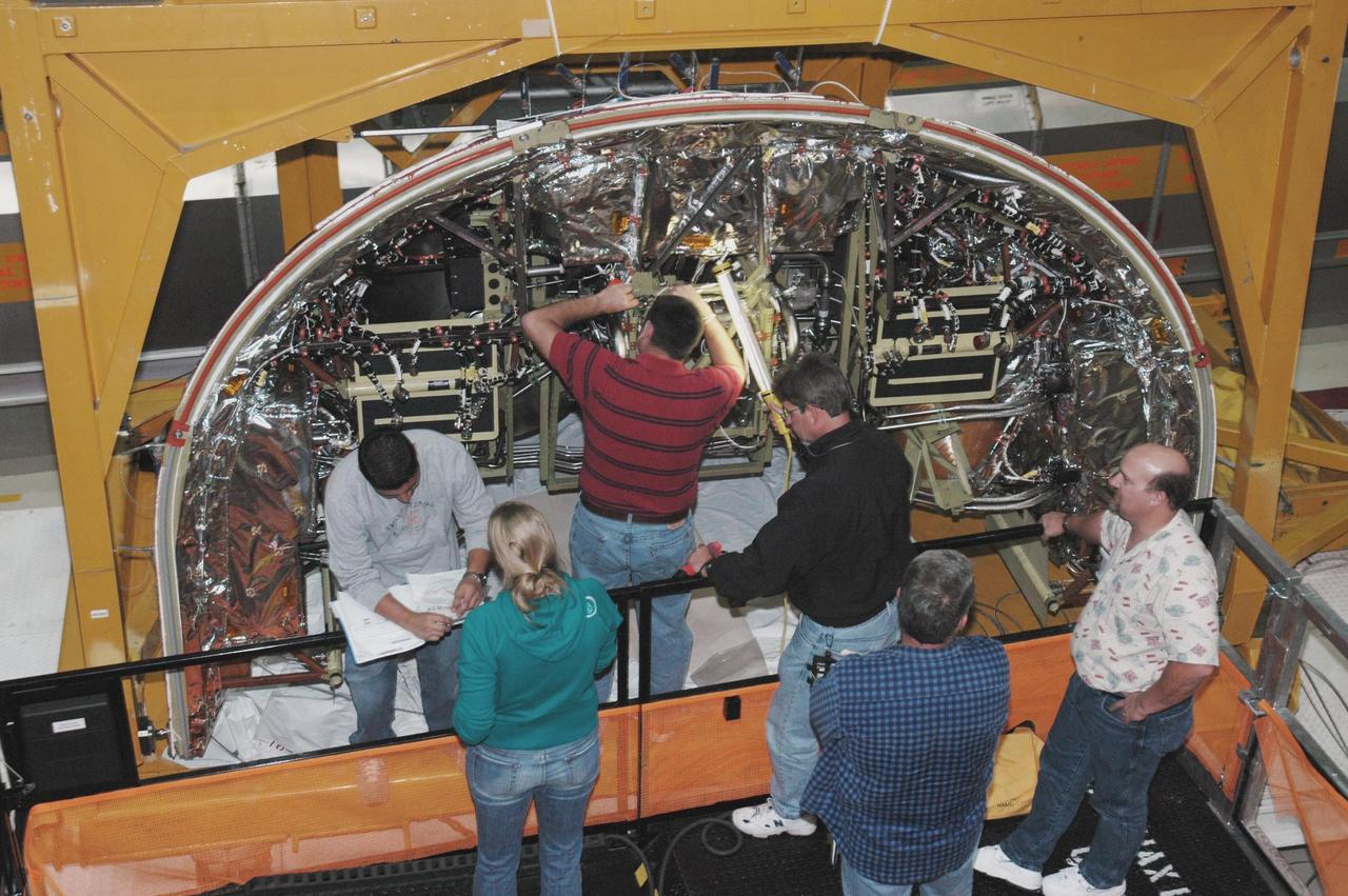 KENNEDY SPACE CENTER, FLA. - In Orbiter Processing Facility Bay 1, technicians work on the Forward Reaction Control System (FRCS) of space shuttle Atlantis as it sits in the transfer aisle prior to installation. The FRCS provides the thrust for attitude (rotational) maneuvers (pitch, yaw and roll) and for small velocity changes along the orbiter axis (translation maneuvers). Processing of Atlantis is under way for mission STS-115, the 19th flight to the International Space Station.