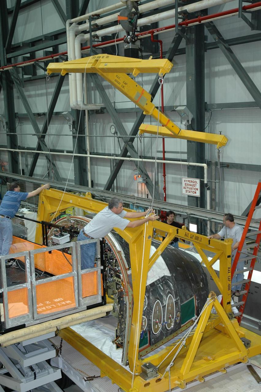 KENNEDY SPACE CENTER, FLA. -- Inside NASA Kennedy Space Center’s Orbiter Processing Facility Bay 1, workers secure the overhead crane to the sling placed round the forward reaction control system that will be installed on Atlantis. When ready, the shuttle equipment will be lifted for installation. The forward reaction control system is located in the forward fuselage nose area. During ascent of the space shuttle, it provides the thrust for attitude (rotational) maneuvers (pitch, yaw and roll) and for small velocity changes along the orbiter axis (translation maneuvers).