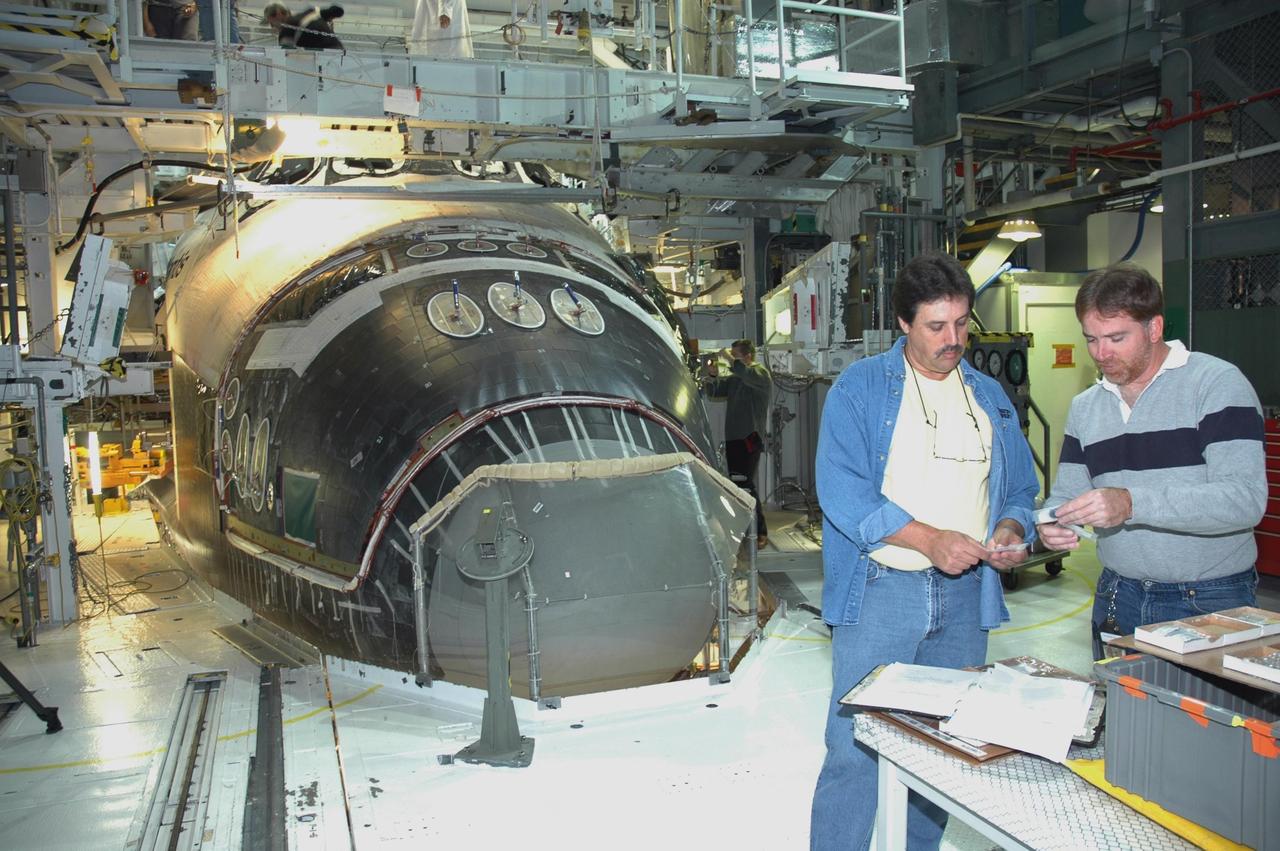 KENNEDY SPACE CENTER, FLA. -- In NASA Kennedy Space Center’s Orbiter Processing Facility Bay 1, technicians check details for the installation of the forward reaction control system on Atlantis (behind them). The control system fits just behind the nose cone and provides the thrust for attitude (rotational) maneuvers (pitch, yaw and roll) and for small velocity changes along the orbiter axis (translation maneuvers). Processing of Atlantis is under way for mission STS-115, the 19th flight to the International Space Station.