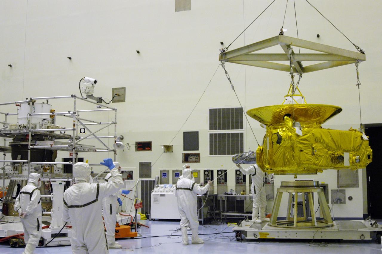 KENNEDY SPACE CENTER, FLA. -- In the Payload Hazardous Servicing Facility at NASA Kennedy Space Center, workers in clean room suits help lift the New Horizons spacecraft from its work stand. It will be moved across the room and mated with the third stage, or upper booster, a Boeing STAR 48 solid-propellant kick motor. The launch vehicle for New Horizons is the Atlas V rocket, scheduled to launch from Cape Canaveral Air Force Station, Fla., during a 35-day window that opens Jan. 11, and fly through the Pluto system as early as summer 2015.