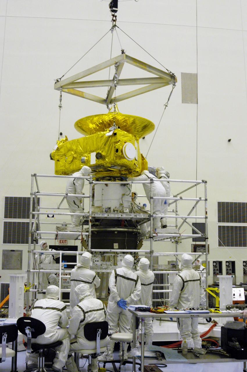KENNEDY SPACE CENTER, FLA. -- In the Payload Hazardous Servicing Facility at NASA Kennedy Space Center, workers in clean room suits secure the New Horizons spacecraft with the third stage, or upper booster, a Boeing STAR 48 solid-propellant kick motor. The launch vehicle for New Horizons is the Atlas V rocket, scheduled to launch from Cape Canaveral Air Force Station, Fla., during a 35-day window that opens Jan. 11, and fly through the Pluto system as early as summer 2015.