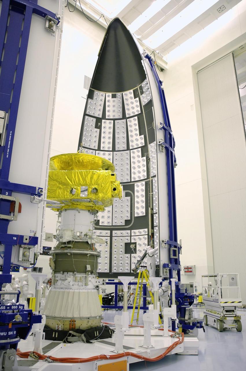 KENNEDY SPACE CENTER, FLA. - In the Payload Hazardous Servicing Facility, clean-suit garbed workers prepare the first fairing section (in the background) that will encapsulate the New Horizons spacecraft at left for flight. The fairing protects the spacecraft during launch and flight through the atmosphere. Once out of the atmosphere, the fairing is jettisoned. The compact 1,060-pound New Horizons probe carries seven scientific instruments that will characterize the global geology and geomorphology of Pluto and its moon Charon, map their surface compositions and temperatures, and examine Pluto's complex atmosphere. After that, flybys of Kuiper Belt objects from even farther in the solar system may be undertaken in an extended mission. New Horizons is the first mission in NASA's New Frontiers program of medium-class planetary missions. The spacecraft, designed for NASA by the Johns Hopkins University Applied Physics Laboratory in Laurel, Md., will fly by Pluto and Charon as early as summer 2015.