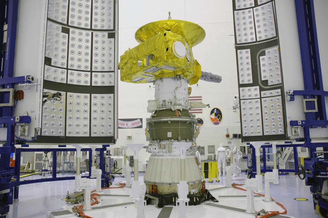 KENNEDY SPACE CENTER, FLA. - In the Payload Hazardous Servicing Facility, the two fairing sections are ready to be moved in place around the New Horizons spacecraft (in center) for encapsulation. The fairing protects the spacecraft during launch and flight through the atmosphere. Once out of the atmosphere, the fairing is jettisoned. The compact 1,060-pound New Horizons probe carries seven scientific instruments that will characterize the global geology and geomorphology of Pluto and its moon Charon, map their surface compositions and temperatures, and examine Pluto's complex atmosphere. After that, flybys of Kuiper Belt objects from even farther in the solar system may be undertaken in an extended mission. New Horizons is the first mission in NASA's New Frontiers program of medium-class planetary missions. The spacecraft, designed for NASA by the Johns Hopkins University Applied Physics Laboratory in Laurel, Md., will fly by Pluto and Charon as early as summer 2015.
