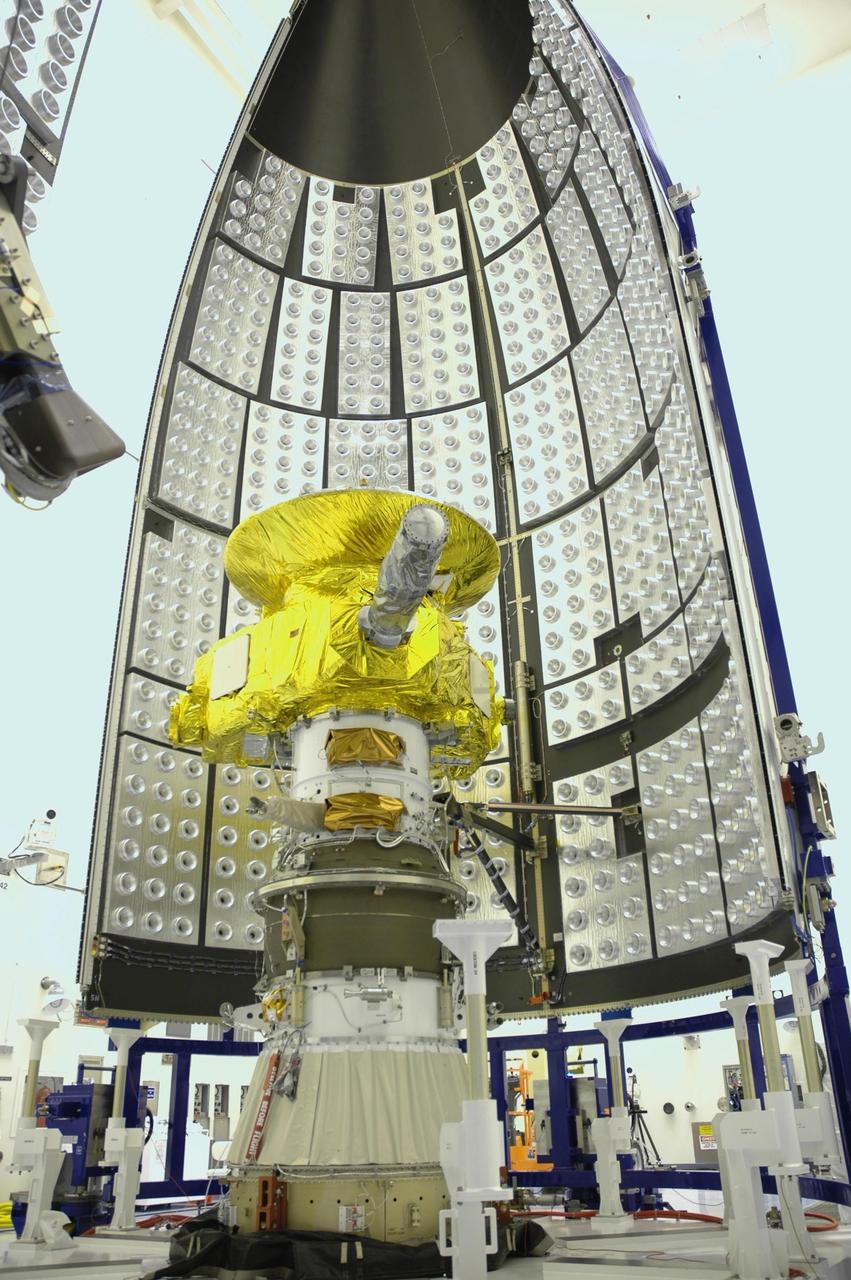 KENNEDY SPACE CENTER, FLA. - In the Payload Hazardous Servicing Facility, the New Horizons spacecraft waits for encapsulation within the fairing sections waiting nearby. The fairing protects the spacecraft during launch and flight through the atmosphere. Once out of the atmosphere, the fairing is jettisoned. The compact 1,060-pound New Horizons probe carries seven scientific instruments that will characterize the global geology and geomorphology of Pluto and its moon Charon, map their surface compositions and temperatures, and examine Pluto's complex atmosphere. After that, flybys of Kuiper Belt objects from even farther in the solar system may be undertaken in an extended mission. New Horizons is the first mission in NASA's New Frontiers program of medium-class planetary missions. The spacecraft, designed for NASA by the Johns Hopkins University Applied Physics Laboratory in Laurel, Md., will fly by Pluto and Charon as early as summer 2015.