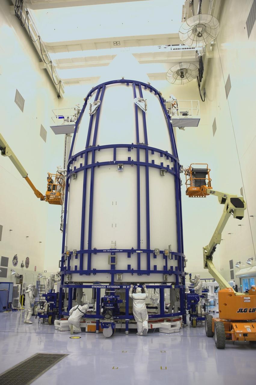 KENNEDY SPACE CENTER, FLA. - In the Payload Hazardous Servicing Facility, clean-suit garbed workers secure the fairing sections around the New Horizons spacecraft for encapsulation. The fairing protects the spacecraft during launch and flight through the atmosphere. Once out of the atmosphere, the fairing is jettisoned. The compact 1,060-pound New Horizons probe carries seven scientific instruments that will characterize the global geology and geomorphology of Pluto and its moon Charon, map their surface compositions and temperatures, and examine Pluto's complex atmosphere. After that, flybys of Kuiper Belt objects from even farther in the solar system may be undertaken in an extended mission. New Horizons is the first mission in NASA's New Frontiers program of medium-class planetary missions. The spacecraft, designed for NASA by the Johns Hopkins University Applied Physics Laboratory in Laurel, Md., will fly by Pluto and Charon as early as summer 2015.