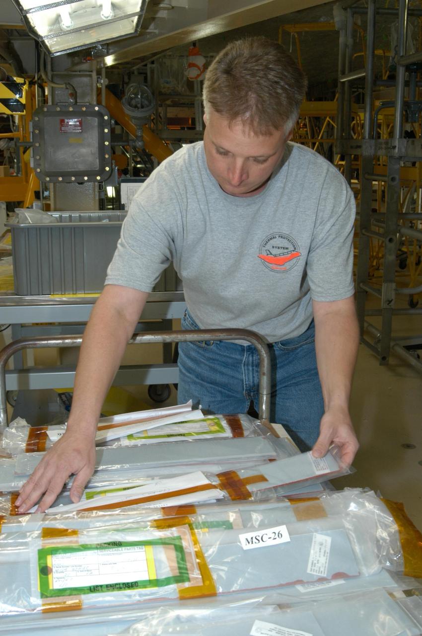KENNEDY SPACE CENTER, FLA. -- United Space Alliance technician Larry Tanner pulls strips of gap filler to install on the orbiter Discovery, which is being processed in Orbiter Processing Facility Bay 3 at NASA’s Kennedy Space Center. This work is being performed due to two gap fillers that were protruding from the underside of Discovery on the first Return to Flight mission, STS-114. New installation procedures have been developed to ensure the gap fillers stay in place and do not pose any hazard during the shuttle's re-entry to the atmosphere. Discovery is the scheduled orbiter for the second space shuttle mission in the return-to-flight sequence.