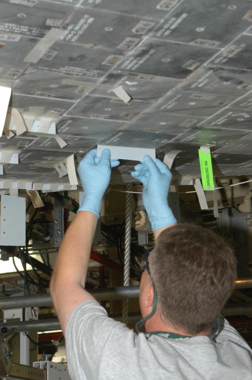 KENNEDY SPACE CENTER, FLA. --   United Space Alliance technician Larry Tanner makes a fit check on the piece of gap filler to be installed on the orbiter Discovery, which is being processed in Orbiter Processing Facility Bay 3 at NASA’s Kennedy Space Center.  This work is being performed due to two gap fillers that were protruding from the underside of Discovery on the first Return to Flight mission, STS-114. New installation procedures have been developed to ensure the gap fillers stay in place and do not pose any hazard during the shuttle's re-entry to the atmosphere. Discovery is the scheduled orbiter for the second space shuttle mission in the return-to-flight sequence.