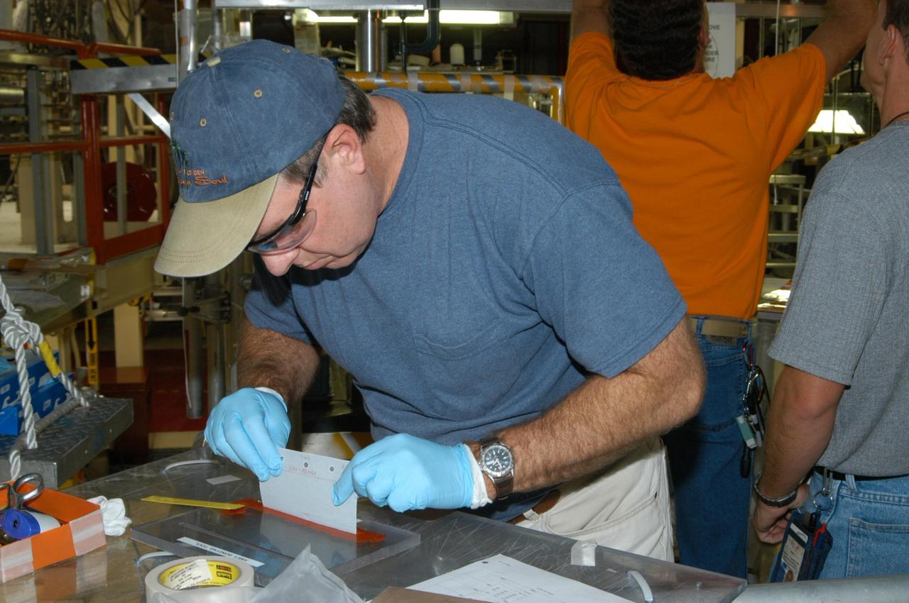 KENNEDY SPACE CENTER, FLA. --  United Space Alliance technician Dell Chapman applies the glue (red) known as RTV, or room temperature vulcanization, to a strip of gap filler before installation on the orbiter Discovery, which is being processed in Orbiter Processing Facility Bay 3 at NASA’s Kennedy Space Center.  This work is being performed due to two gap fillers that were protruding from the underside of Discovery on the first Return to Flight mission, STS-114. New installation procedures have been developed to ensure the gap fillers stay in place and do not pose any hazard during the shuttle's re-entry to the atmosphere. Discovery is the scheduled orbiter for the second space shuttle mission in the return-to-flight sequence.