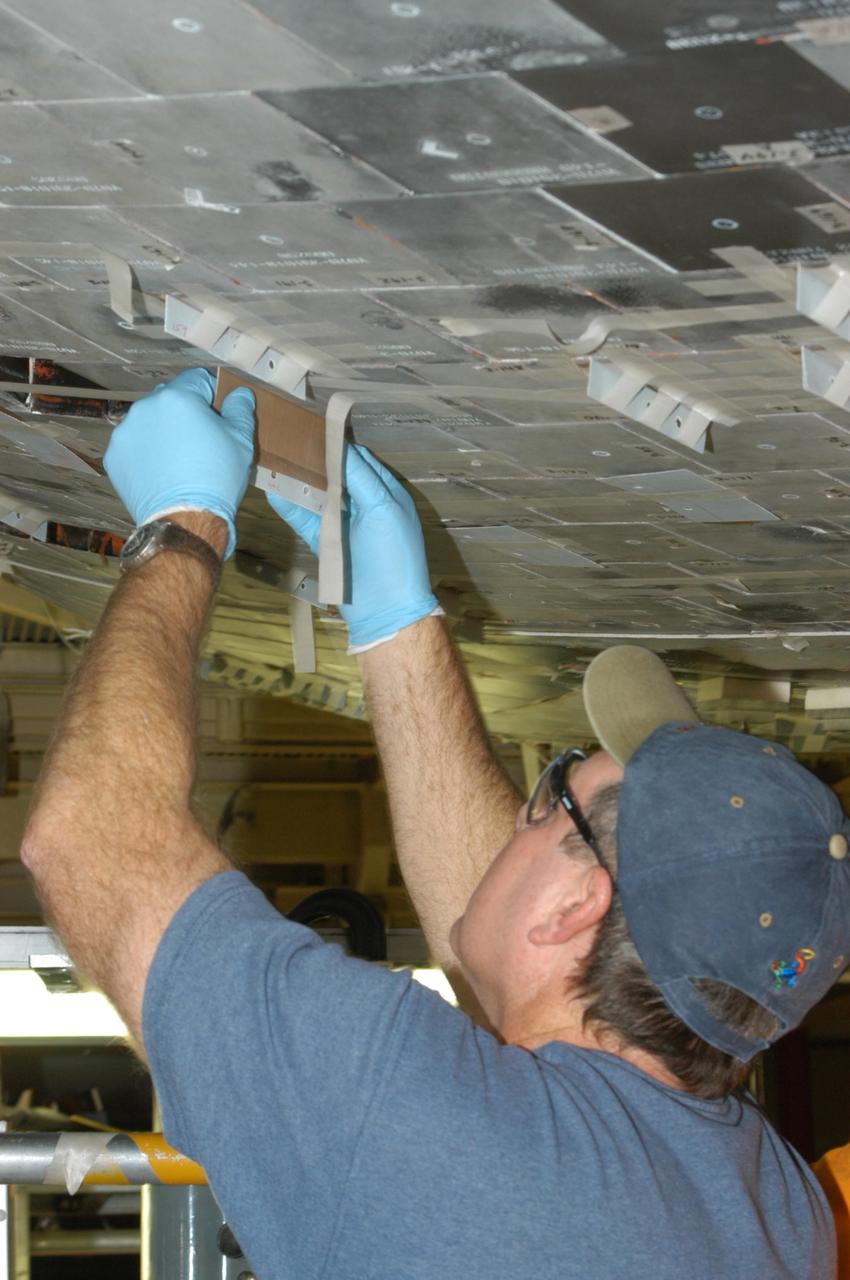 KENNEDY SPACE CENTER, FLA. --  United Space Alliance technician Dell Chapman installs the gap filler between tiles on the orbiter Discovery, which is being processed in Orbiter Processing Facility Bay 3 at NASA’s Kennedy Space Center. This work is being performed due to two gap fillers that were protruding from the underside of Discovery on the first Return to Flight mission, STS-114. New installation procedures have been developed to ensure the gap fillers stay in place and do not pose any hazard during the shuttle's re-entry to the atmosphere. Discovery is the scheduled orbiter for the second space shuttle mission in the return-to-flight sequence.