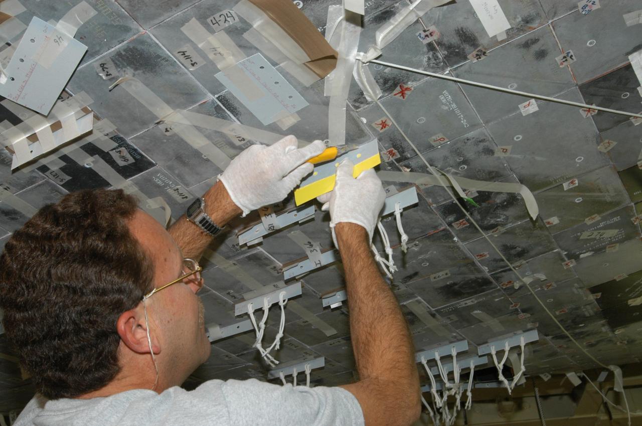 KENNEDY SPACE CENTER, FLA. --  United Space Alliance technician Gene Peavler cuts the excess gap filler away from the tile on the orbiter Discovery, which is being processed in Orbiter Processing Facility Bay 3 at NASA’s Kennedy Space Center.  This work is being performed due to two gap fillers that were protruding from the underside of Discovery on the first Return to Flight mission, STS-114. New installation procedures have been developed to ensure the gap fillers stay in place and do not pose any hazard during the shuttle's re-entry to the atmosphere. Discovery is the scheduled orbiter for the second space shuttle mission in the return-to-flight sequence.