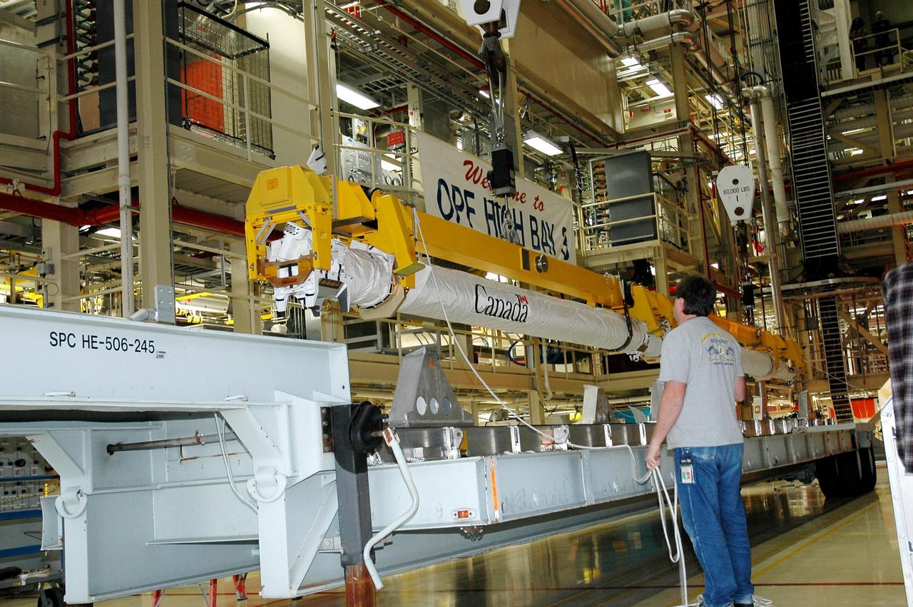 KENNEDY SPACE CENTER, FLA. -- In Orbiter Processing Facility Bay 3, a crane carries the new orbital boom sensor system to be installed in Discovery’s payload bay. The previous boom was removed for repairs on the manipulator positioning mechanism, the pedestals that hold the boom in place in the payload bay. Discovery is the designated orbiter for the second return-to-flight mission, STS-121. The mission is scheduled no earlier than mid-May.