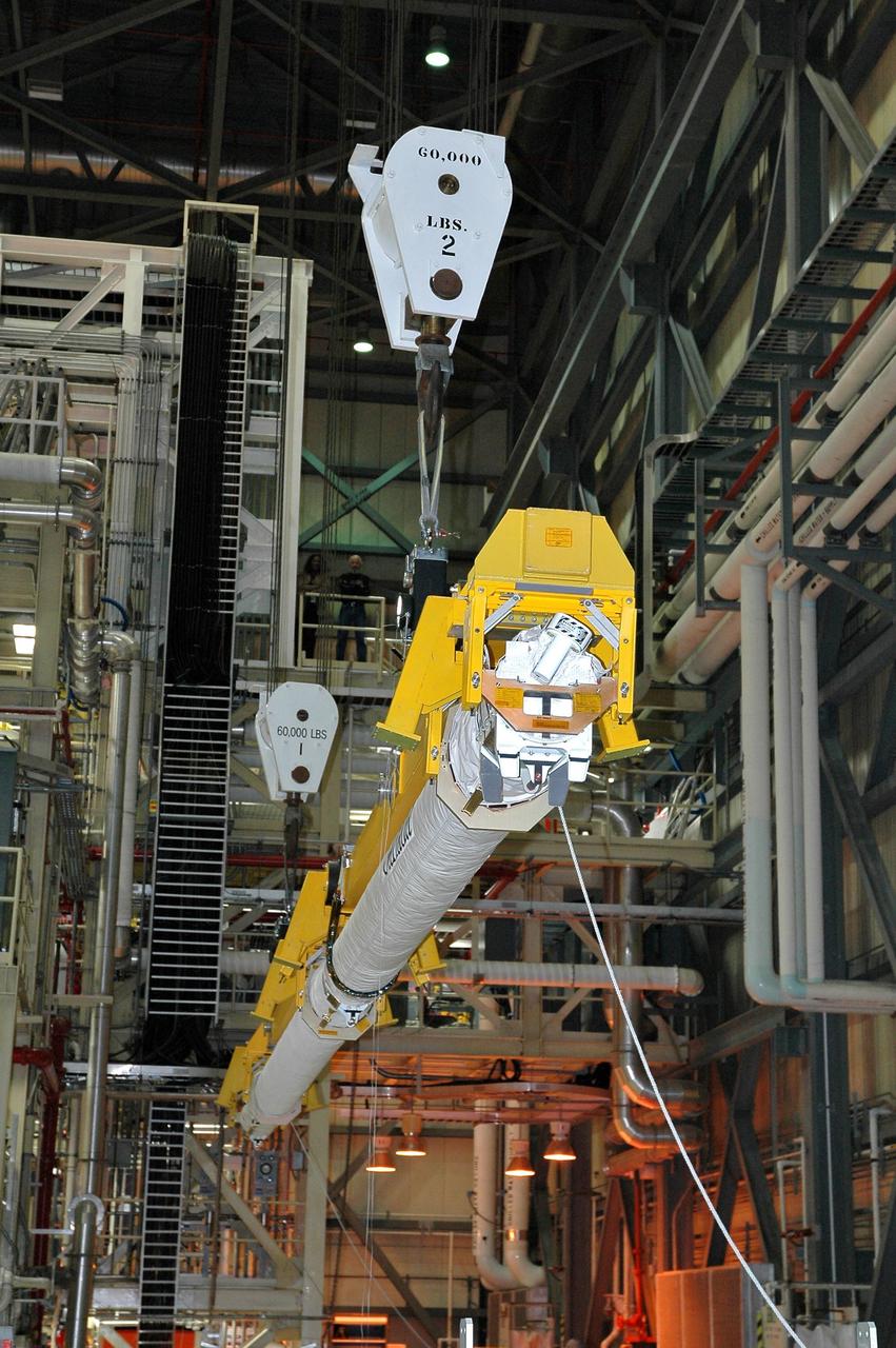 KENNEDY SPACE CENTER, FLA. -- In Orbiter Processing Facility Bay 3, the new orbital boom sensor system is lowered into Discovery’s payload bay. The previous boom was removed for repairs on the manipulator positioning mechanism, the pedestals that hold the boom in place in the payload bay. Discovery is the designated orbiter for the second return-to-flight mission, STS-121. The mission is scheduled no earlier than mid-May.