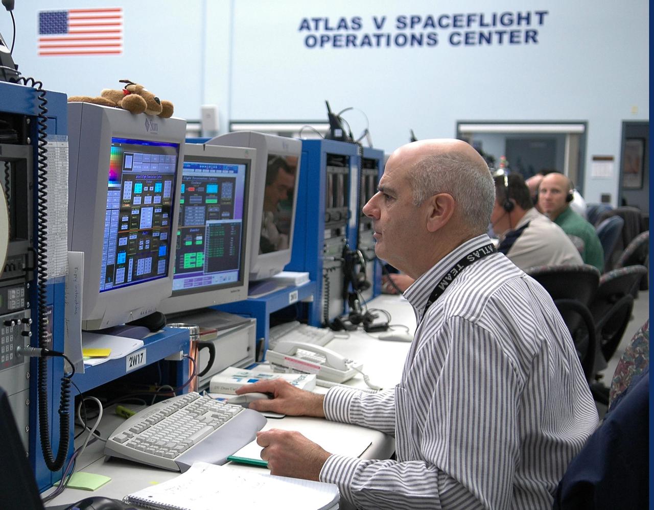 KENNEDY SPACE CENTER, FLA. - In the Atlas V Spaceflight Operations Center on Cape Canaveral Air Force Station, Ed Biggs (foreground), a fluids software engineer for Lockheed Martin, and other members of the New Horizons team take part in a dress rehearsal for the launch scheduled in mid-January. New Horizons carries seven scientific instruments that will characterize the global geology and geomorphology of Pluto and its moon Charon, map their surface compositions and temperatures, and examine Pluto's complex atmosphere. After that, flybys of Kuiper Belt objects from even farther in the solar system may be undertaken in an extended mission. New Horizons is the first mission in NASA's New Frontiers program of medium-class planetary missions. The spacecraft, designed for NASA by the Johns Hopkins University Applied Physics Laboratory in Laurel, Md., will launch aboard a Lockheed Martin Atlas V rocket and fly by Pluto and Charon as early as summer 2015.