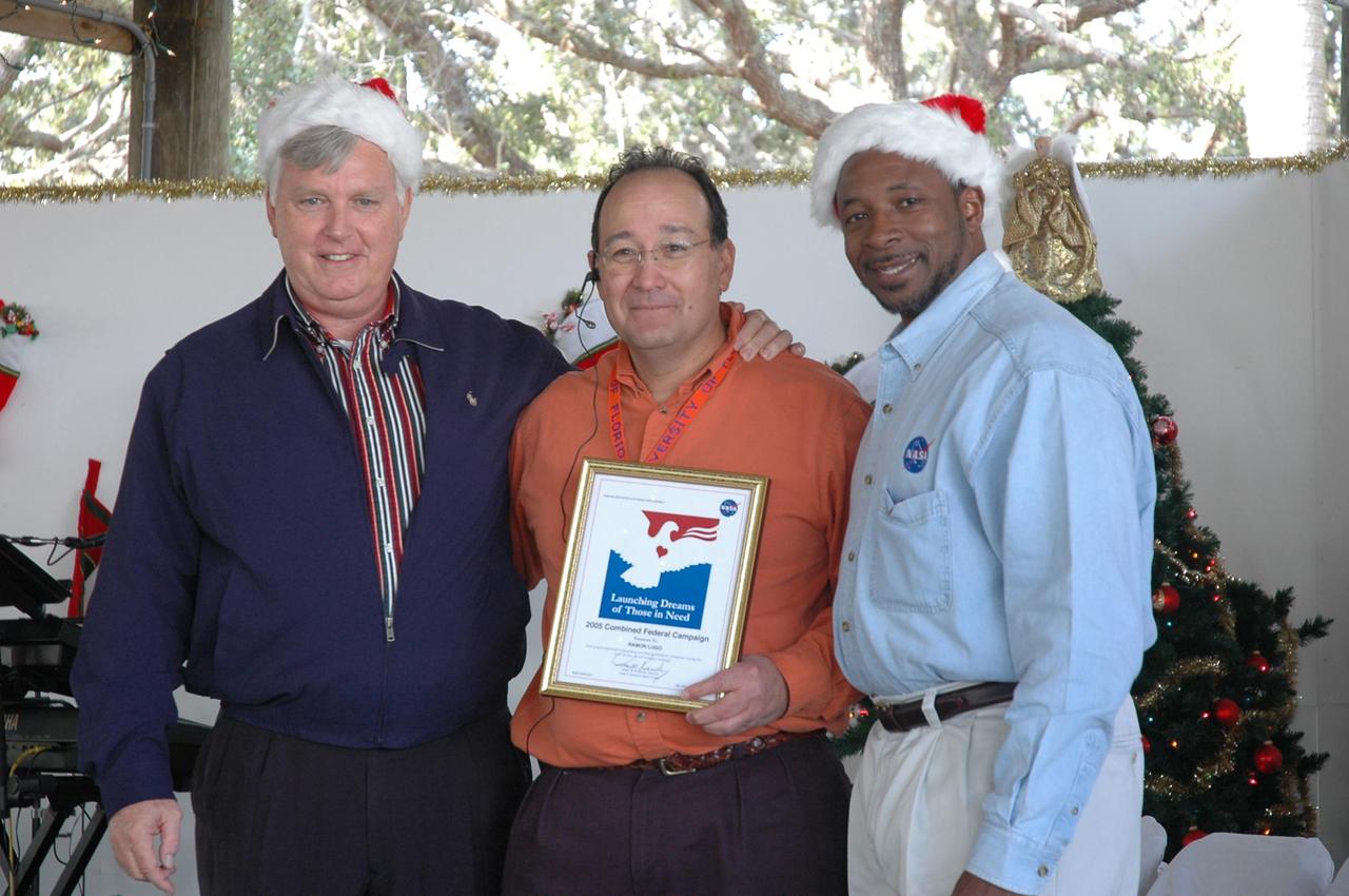 KENNEDY SPACE CENTER, FLA. - Launch Services Program Deputy Director Ray Lugo (center) shows off a certificate of appreciation he received for his leadership and enthusiasm in his role as chairperson of KSC's Combined Federal Campaign.  From left are Center Director Jim Kennedy, Lugo and Deputy Director Woodrow Whitlow. The NASA civil service work force donated $434,627.40 in this year's campaign, the highest amount ever raised. The occasion was a holiday dinner and celebration at KARS Park I on Merritt Island, Fla., hosted by Center Director Jim Kennedy for NASA civil service employees. The theme of the celebration was "Launching Dreams of Those in Need." The event was sponsored by the Change Leaders Network and the Combined Federal Campaign Cabinet.