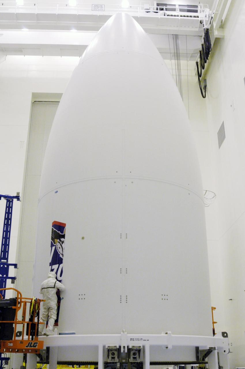KENNEDY SPACE CENTER, FLA. - A technician installs the first strip of the New Horizons mission decal on the spacecraft fairing in the Payload Hazardous Servicing Facility. The last strip will be installed on the fairing after the spacecraft is delivered to Pad 41 on Dec. 17. New Horizons carries seven scientific instruments that will characterize the global geology and geomorphology of Pluto and its moon Charon, map their surface compositions and temperatures, and examine Pluto's complex atmosphere. After that, flybys of Kuiper Belt objects from even farther in the solar system may be undertaken in an extended mission. New Horizons is the first mission in NASA's New Frontiers program of medium-class planetary missions. The spacecraft, designed for NASA by the Johns Hopkins University Applied Physics Laboratory in Laurel, Md., will launch aboard a Lockheed Martin Atlas V rocket and fly by Pluto and Charon as early as summer 2015.