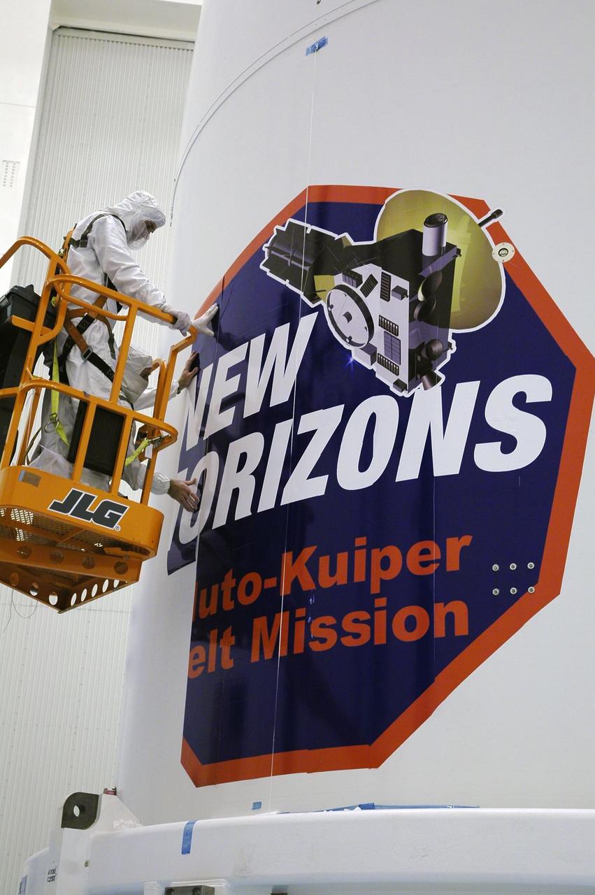 KENNEDY SPACE CENTER, FLA. - Technicians install strips of the New Horizons mission decal on the spacecraft fairing in the Payload Hazardous Servicing Facility. The last strip will be installed on the fairing after the spacecraft is delivered to Pad 41 on Dec. 17. New Horizons carries seven scientific instruments that will characterize the global geology and geomorphology of Pluto and its moon Charon, map their surface compositions and temperatures, and examine Pluto's complex atmosphere. After that, flybys of Kuiper Belt objects from even farther in the solar system may be undertaken in an extended mission. New Horizons is the first mission in NASA's New Frontiers program of medium-class planetary missions. The spacecraft, designed for NASA by the Johns Hopkins University Applied Physics Laboratory in Laurel, Md., will launch aboard a Lockheed Martin Atlas V rocket and fly by Pluto and Charon as early as summer 2015.
