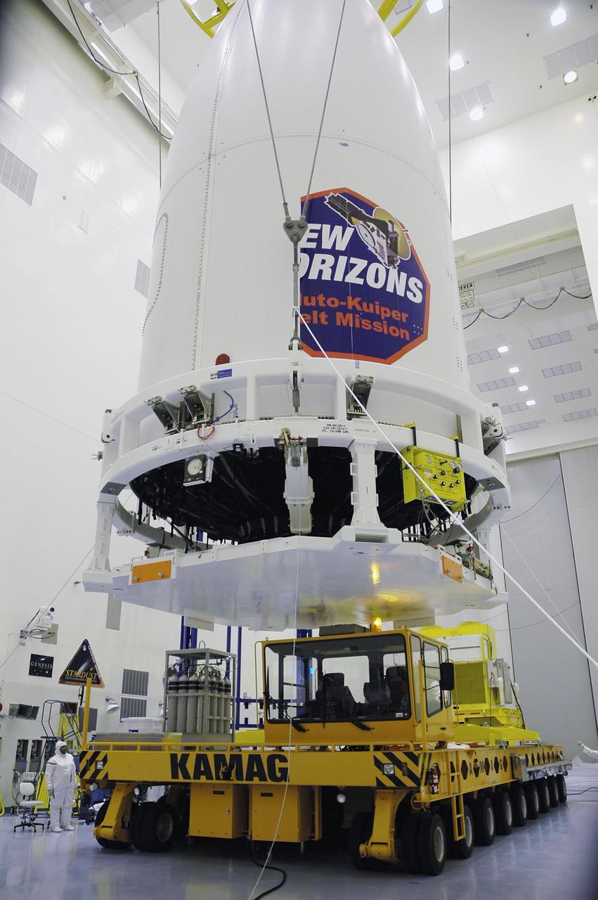 KENNEDY SPACE CENTER, FLA. - In the Payload Hazardous Servicing Facility, technicians lower New Horizons onto a transporter for its move to Complex 41 on Cape Canaveral Air Force Station. The last strip of the mission decal will be installed on the fairing after the spacecraft is delivered to the pad. New Horizons carries seven scientific instruments that will characterize the global geology and geomorphology of Pluto and its moon Charon, map their surface compositions and temperatures, and examine Pluto's complex atmosphere. After that, flybys of Kuiper Belt objects from even farther in the solar system may be undertaken in an extended mission. New Horizons is the first mission in NASA's New Frontiers program of medium-class planetary missions. The spacecraft, designed for NASA by the Johns Hopkins University Applied Physics Laboratory in Laurel, Md., will launch aboard a Lockheed Martin Atlas V rocket and fly by Pluto and Charon as early as summer 2015.