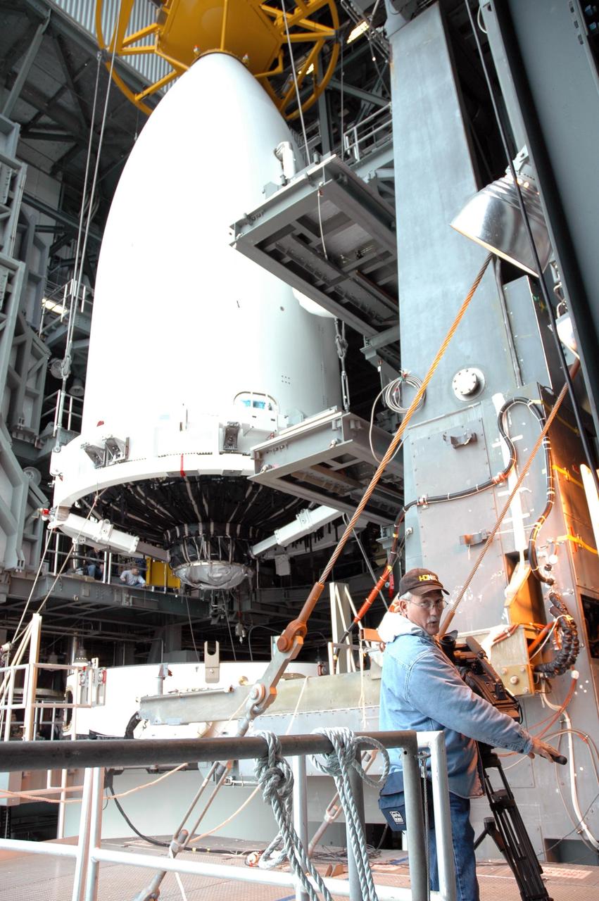 KENNEDY SPACE CENTER, FLA. - InDyne employee Mic Miracle captures on video the arrival of the fairing enclosing New Horizons at the top of a Lockheed Martin Atlas V launch vehicle in the Vertical Integration Facility at Complex 41 on Cape Canaveral Air Force Station. New Horizons carries seven scientific instruments that will characterize the global geology and geomorphology of Pluto and its moon Charon, map their surface compositions and temperatures, and examine Pluto's complex atmosphere. After that, flybys of Kuiper Belt objects from even farther in the solar system may be undertaken in an extended mission. New Horizons is the first mission in NASA's New Frontiers program of medium-class planetary missions. The spacecraft, designed for NASA by the Johns Hopkins University Applied Physics Laboratory in Laurel, Md., will launch aboard a Lockheed Martin Atlas V rocket and fly by Pluto and Charon as early as summer 2015.