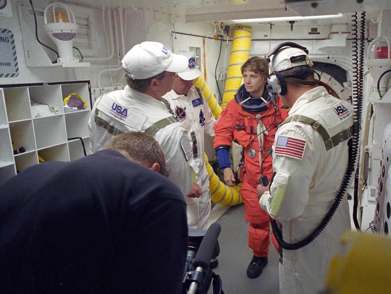 KENNEDY SPACE CENTER, FLA. - With the help of the Closeout Crew in the White Room on Launch Pad 39B, STS-114 Commander Eileen Collins adjusts her launch suit before entering Space Shuttle Discovery. The crew is taking part in a full dress rehearsal for launch, including countdown and culminating in main engine cutoff. The rehearsal is the final part of Terminal Countdown Demonstration Test (TCDT) activities that the crew has been involved in for three days. TCDT provides the crew of each mission an opportunity to participate in various simulated countdown activities, including equipment familiarization and emergency egress training. STS-114 is the first Return to Flight mission to the International Space Station. The launch window extends July 13 through July 31.