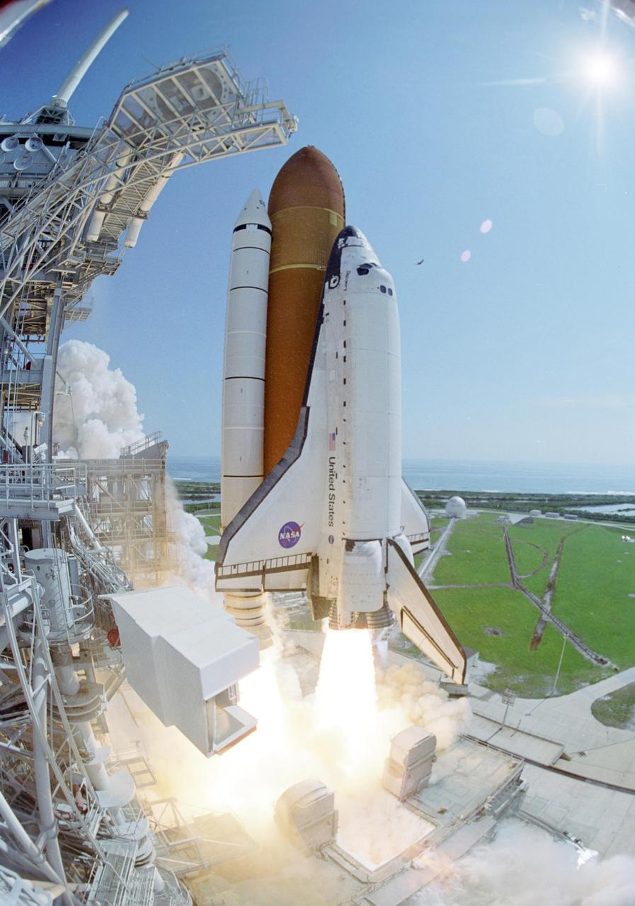 KENNEDY SPACE CENTER, FLA. - A fish-eye view shows Space Shuttle Discovery moments after liftoff from Launch Pad 39B on the historic Return to Flight mission STS-114. At left is the Fixed Service Structure with the White Room appearing to be suspended in mid-air. The White Room provides the astronauts access into the orbiter. The liftoff occurred at 10:39 a.m. EDT. On this mission to the International Space Station the crew will perform inspections on-orbit for the first time of all of the Reinforced Carbon-Carbon (RCC) panels on the leading edge of the wings and the Thermal Protection System tiles using the new Canadian-built Orbiter Boom Sensor System and the data from 176 impact and temperature sensors. Mission Specialists will also practice repair techniques on RCC and tile samples during a spacewalk in the payload bay. During two additional spacewalks, the crew will install the External Stowage Platform-2, equipped with spare part assemblies, and a replacement Control Moment Gyroscope contained in the Lightweight Multi-Purpose Experiment Support Structure. The 12-day mission is expected to end with touchdown at the Shuttle Landing Facility on Aug. 7.