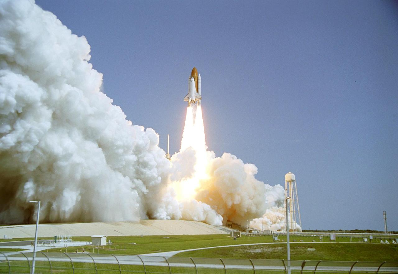 KENNEDY SPACE CENTER, FLA. -  As billows of smoke and steam roll away, Space Shuttle Discovery leaps from Launch Pad 39B on the historic Return to Flight mission STS-114.  Liftoff occurred at 10:39 a.m. EDT. At right is the 290-foot water tower that holds the 300,000 gallons of water that flood the pad for sound suppression.  This is the 114th Space Shuttle flight and the 31st for Discovery.  The 12-day mission is expected to end with touchdown at the Shuttle Landing Facility on Aug. 7.  On this mission to the International Space Station the crew will perform inspections on-orbit for the first time of all of the Reinforced Carbon-Carbon (RCC) panels on the leading edge of the wings and the Thermal Protection System tiles using the new Canadian-built Orbiter Boom Sensor System and the data from 176 impact and temperature sensors. Mission Specialists will also practice repair techniques on RCC and tile samples during a spacewalk in the payload bay.  During two additional spacewalks, the crew will install the External Stowage Platform-2, equipped with spare part assemblies, and a replacement Control Moment Gyroscope contained in the Lightweight Multi-Purpose Experiment Support Structure.