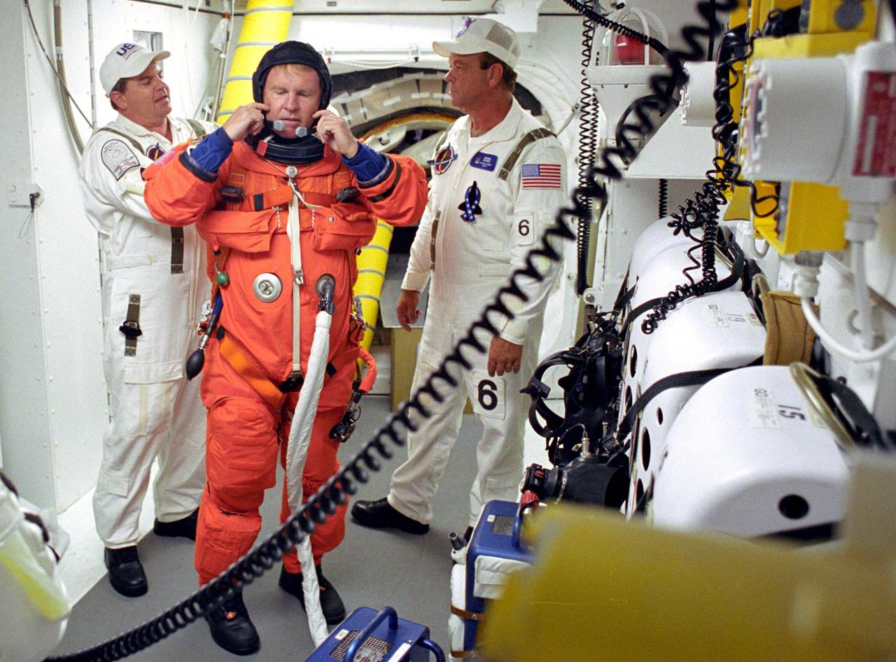 KENNEDY SPACE CENTER, FLA. - STS-114 Mission Specialist Andrew Thomas is helped by the Closeout Crew with his launch and entry suit before entering Space Shuttle Discovery. The Return to Flight mission to the International Space Station carries the External Stowage Platform-2, equipped with spare part assemblies, and a replacement Control Moment Gyroscope contained in the Lightweight Multi-Purpose Experiment Support Structure and Multi-Purpose Logistics Module Raffaello, housing 15 tons of hardware and supplies that will be transferred to the Station after the Shuttle docks to the complex . On this mission, the crew will perform inspections on-orbit for the first time of all of the Reinforced Carbon-Carbon (RCC) panels on the leading edge of the wings and the Thermal Protection System tiles using the new Canadian-built Orbiter Boom Sensor System and the data from 176 impact and temperature sensors. Mission Specialists will also practice repair techniques on RCC and tile samples during a spacewalk in the payload bay.