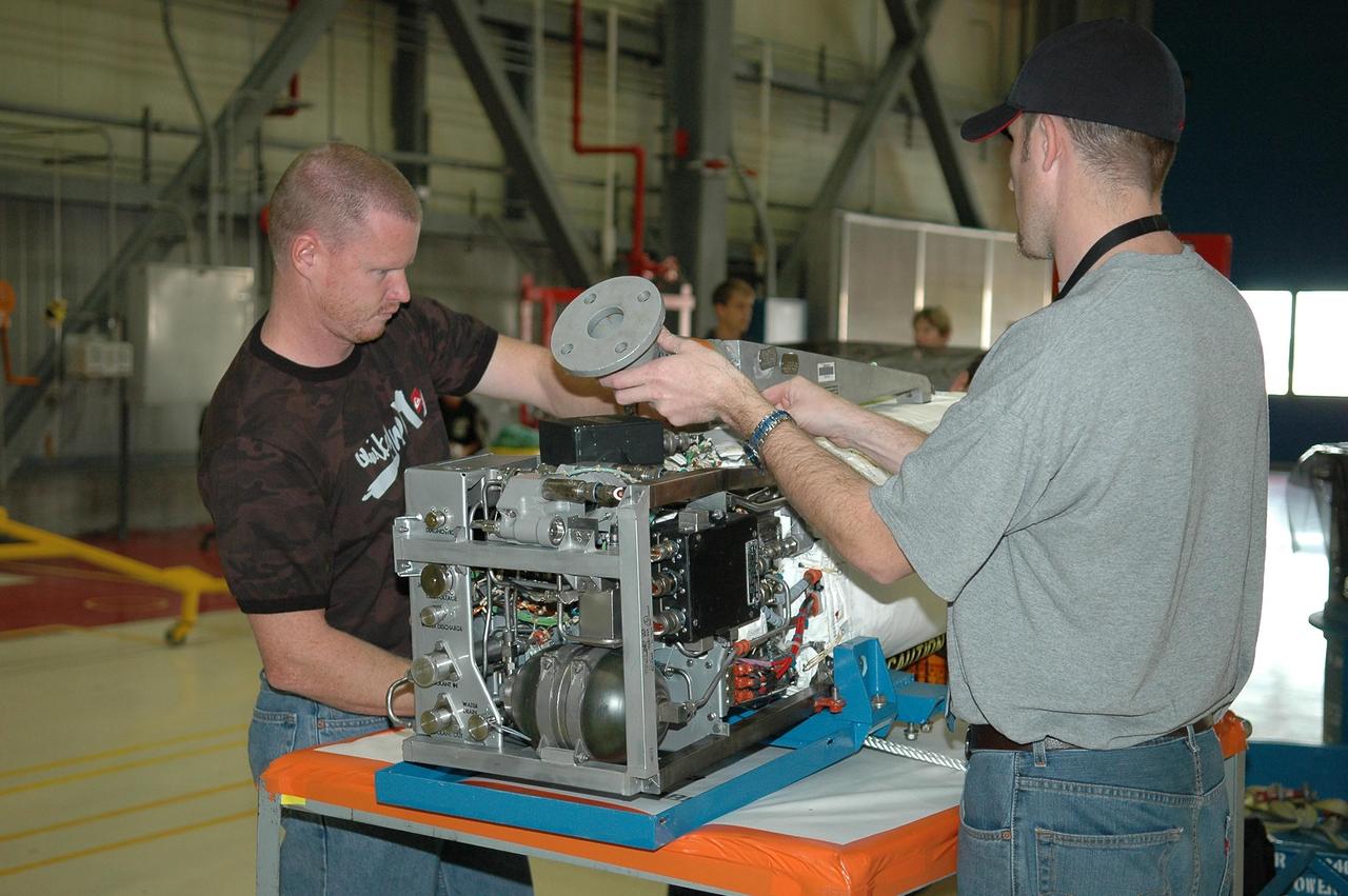 KENNEDY SPACE CENTER, FLA. - In NASA Kennedy Space Center’s Orbiter Processing Facility bay 3, technicians begin dismantling the fuel cell removed from the orbiter Discovery.  Fuel cells are located under the forward portion of the payload bay.  They make power for the orbiter by mixing hydrogen and oxygen to produce electricity.  Fuel cells also create potable water that is pumped into storage tanks for the crew to use in orbit.  Discovery is the designated orbiter for the second return-to-flight mission, STS-121, scheduled for launch in May.  Photo credit: NASA/Kim Shiflett