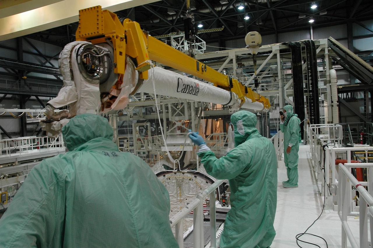 KENNEDY SPACE CENTER, FLA. -   In the Orbiter Processing Facility bay 1 at NASA Kennedy Space Center, engineers stand by as the remote manipulator system, or boom, is lowered toward Atlantis’ payload bay for installation.  Atlantis is the designated orbiter for mission STS-115, the 19th assembly flight to the International Space Station.  The payload includes the P3/P4 solar arrays. The launch planning window has not been determined yet for STS-115.