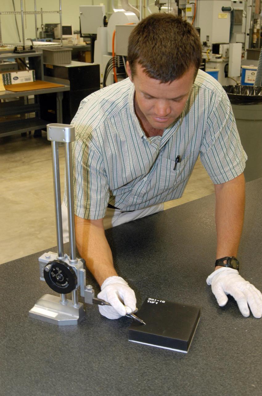 KENNEDY SPACE CENTER, FLA. -  In the Thermal Protection System Facility, Tim Wright, engineering manager with United Space Alliance, tests a new tile, called "Boeing replacement insulation" or "BRI-18."  The new tiles will gradually replace older tiles around main landing gear doors, external tank doors and nose landing gear doors.  Currently, 10 tiles have been processed inside the facility. Discovery will receive the first BRI-18 tiles. Technicians inside the Orbiter Processing Facility are performing fit checks and will begin bonding the tiles to the vehicle this month.  The raw material is manufactured by The Boeing Company in Huntington Beach, Calif.  Replacing older tile with the BRI-18 tile in strategic areas is one of the Columbia Accident Investigation Board's recommendations to strengthen the orbiters.  The tiles are more impact resistant than previous designs, enhancing the crew’s safety.