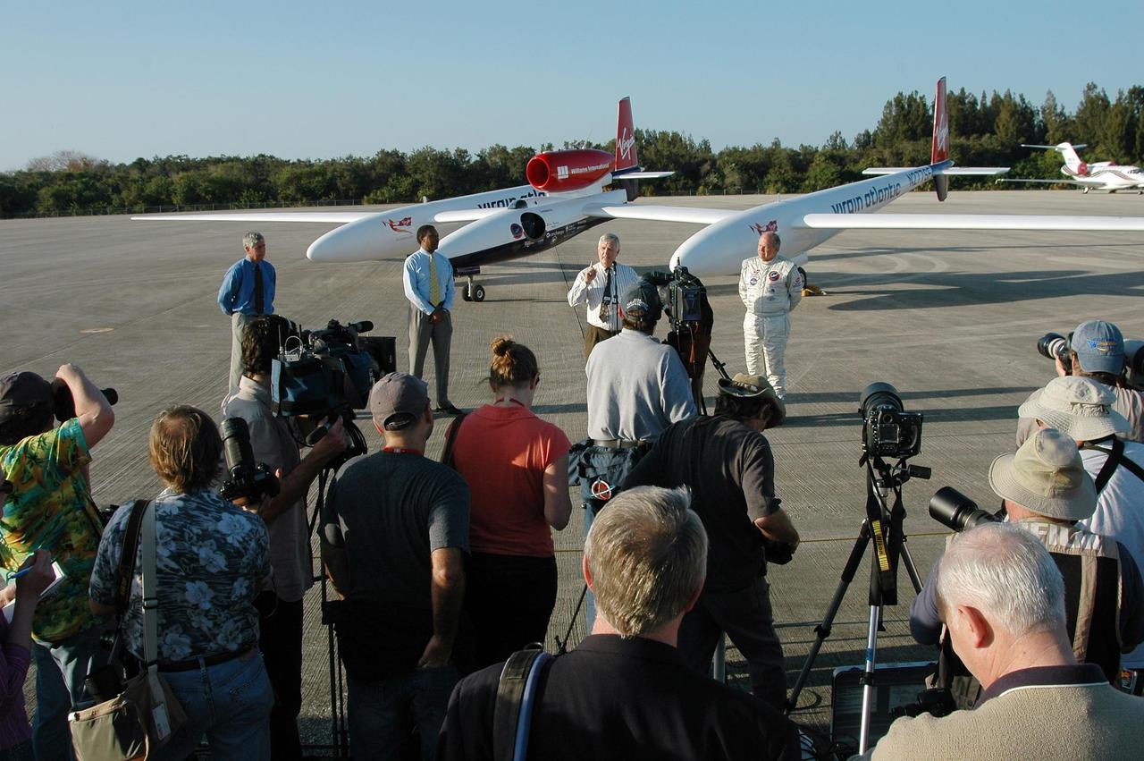KENNEDY SPACE CENTER, FLA. -   After the landing of the Virgin Atlantic Airways GlobalFlyer aircraft at NASA Kennedy Space Center’s Shuttle Landing Facility, Center Director James Kennedy (center, in front of the plane) addresses the media.  At right is the pilot, Steve Fossett.  At left are Jim Ball, KSC Spaceport Development manager, and Winston Scott, executive director of Florida Space Authority. The aircraft is being relocated from Salina, Kan., to the Shuttle Landing Facility to begin preparations for an attempt to set a new world record for the longest flight made by any aircraft. An exact takeoff date for the record-setting flight has not been determined and is contingent on weather and jet-stream conditions. The window for the attempt opens in mid-January, making the flight possible anytime between then and the end of February.  NASA agreed to let Virgin Atlantic Airways use Kennedy's Shuttle Landing Facility as a takeoff site. The facility use is part of a pilot program to expand runway access for non-NASA activities.