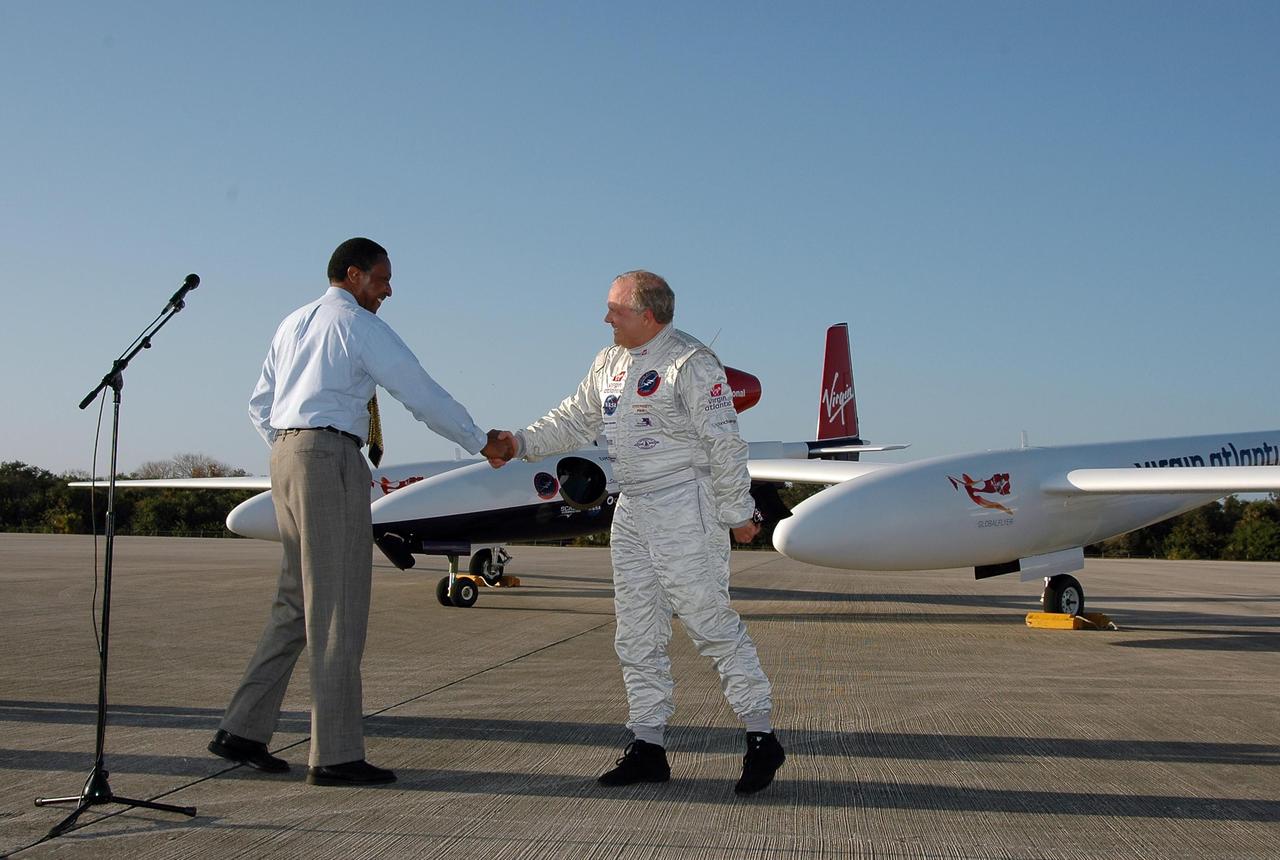 KENNEDY SPACE CENTER, FLA. -  After the landing of the Virgin Atlantic Airways GlobalFlyer aircraft at NASA Kennedy Space Center’s Shuttle Landing Facility,  Winston Scott (left), executive director of Florida Space Authority, brings pilot Steve Fossett to the microphone for a few words to the media. The aircraft is being relocated from Salina, Kan., to the Shuttle Landing Facility to begin preparations for an attempt to set a new world record for the longest flight made by any aircraft. An exact takeoff date for the record-setting flight has not been determined and is contingent on weather and jet-stream conditions. The window for the attempt opens in mid-January, making the flight possible anytime between then and the end of February.  NASA agreed to let Virgin Atlantic Airways use Kennedy's Shuttle Landing Facility as a takeoff site. The facility use is part of a pilot program to expand runway access for non-NASA activities.