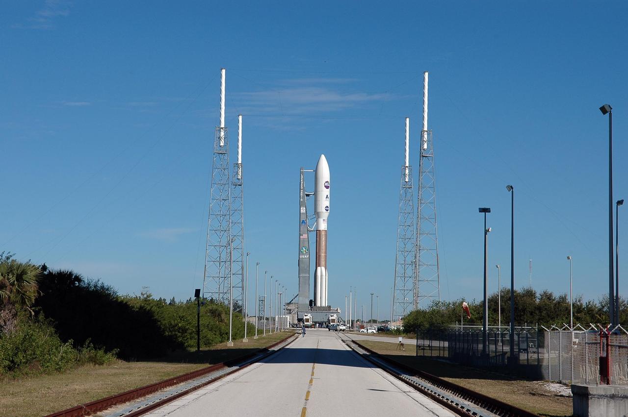 KENNEDY SPACE CENTER, FLA. -  On Complex 41 at Cape Canaveral Air Force Station, the Atlas V expendable launch vehicle with the New Horizons spacecraft has been moved to the pad. Umbilicals have been attached.  Seen near the rocket are lightning masts that support the catenary wire used to provide lightning protection.  Liftoff is scheduled for 1:24 p.m. EST Jan. 17.  After its launch aboard the Atlas V, the compact, 1,050-pound piano-sized probe will get a boost from a kick-stage solid propellant motor for its journey to Pluto. New Horizons will be the fastest spacecraft ever launched, reaching lunar orbit distance in just nine hours and passing Jupiter 13 months later. The New Horizons science payload, developed under direction of Southwest Research Institute, includes imaging infrared and ultraviolet spectrometers, a multi-color camera, a long-range telescopic camera, two particle spectrometers, a space-dust detector and a radio science experiment. The dust counter was designed and built by students at the University of Colorado, Boulder. A launch before Feb. 3 allows New Horizons to fly past Jupiter in early 2007 and use the planet’s gravity as a slingshot toward Pluto. The Jupiter flyby trims the trip to Pluto by as many as five years and provides opportunities to test the spacecraft’s instruments and flyby capabilities on the Jupiter system. New Horizons could reach the Pluto system as early as mid-2015, conducting a five-month-long study possible only from the close-up vantage of a spacecraft.