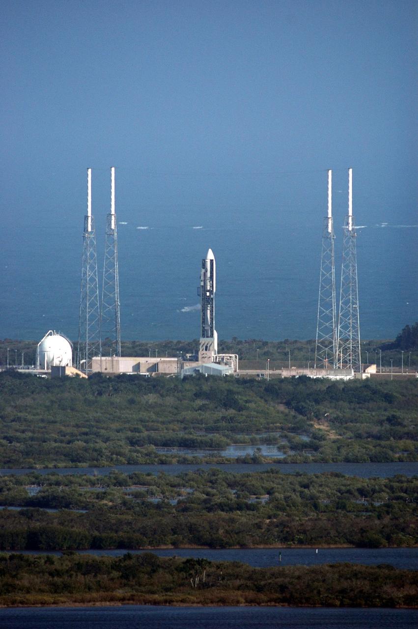 KENNEDY SPACE CENTER, FLA. -  The Atlas V rocket with the New Horizons spacecraft on top sits waiting on the launch pad at Complex 41 at Cape Canaveral Air Force Station in Florida.  The view is from the top of the Vehicle Assembly Building at NASA Kennedy Space Center.  Surrounding the launch vehicle are four lightning masts.  The launch on this date was scrubbed due to high surface winds in the area and has been rescheduled for 1:16 p.m. EST Jan. 18. The compact, 1,050-pound piano-sized probe will get a boost from a kick-stage solid propellant motor for its journey to Pluto. New Horizons will be the fastest spacecraft ever launched, reaching lunar orbit distance in just nine hours and passing Jupiter 13 months later.  The launch at this time allows New Horizons to fly past Jupiter in early 2007 and use the planet’s gravity as a slingshot toward Pluto. The Jupiter flyby trims the trip to Pluto by as many as five years and provides opportunities to test the spacecraft’s instruments and flyby capabilities on the Jupiter system. New Horizons could reach the Pluto system as early as mid-2015, conducting a five-month-long study possible only from the close-up vantage of a spacecraft.  Photo credit: NASA/Kim Shiflett