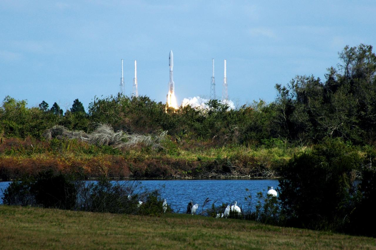 KENNEDY SPACE CENTER, FLA. -- Great white egrets and a great blue heron in the foreground seem to stand watch as NASA's New Horizons spacecraft leaps off the pad on time at 2 p.m. EST aboard an Atlas V rocket from Complex 41 on Cape Canaveral Air Force Station in Florida. This was the third launch attempt in as many days after scrubs due to weather concerns. The compact, 1,050-pound piano-sized probe will get a boost from a kick-stage solid propellant motor for its journey to Pluto. New Horizons will be the fastest spacecraft ever launched, reaching lunar orbit distance in just nine hours and passing Jupiter 13 months later. The New Horizons science payload, developed under direction of Southwest Research Institute, includes imaging infrared and ultraviolet spectrometers, a multi-color camera, a long-range telescopic camera, two particle spectrometers, a space-dust detector and a radio science experiment. The dust counter was designed and built by students at the University of Colorado, Boulder. The launch at this time allows New Horizons to fly past Jupiter in early 2007 and use the planet’s gravity as a slingshot toward Pluto. The Jupiter flyby trims the trip to Pluto by as many as five years and provides opportunities to test the spacecraft’s instruments and flyby capabilities on the Jupiter system. New Horizons could reach the Pluto system as early as mid-2015, conducting a five-month-long study possible only from the close-up vantage of a spacecraft. Photo credit: NASA/Ken Thornsley