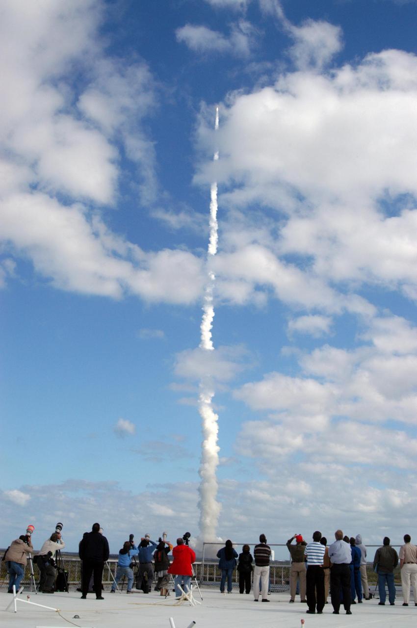 KENNEDY SPACE CENTER, FLA. — Photographers and spectators watch NASA’s New Horizons spacecraft, trailing fire and smoke from the Atlas V rocket that propels it, as it roars into the cloud-scattered sky. Liftoff was on time at 2 p.m. EST from Complex 41 on Cape Canaveral Air Force Station in Florida. This was the third launch attempt in as many days after scrubs due to weather concerns. The compact, 1,050-pound piano-sized probe will get a boost from a kick-stage solid propellant motor for its journey to Pluto. New Horizons will be the fastest spacecraft ever launched, reaching lunar orbit distance in just nine hours and passing Jupiter 13 months later. The New Horizons science payload, developed under direction of Southwest Research Institute, includes imaging infrared and ultraviolet spectrometers, a multi-color camera, a long-range telescopic camera, two particle spectrometers, a space-dust detector and a radio science experiment. The dust counter was designed and built by students at the University of Colorado, Boulder. The launch at this time allows New Horizons to fly past Jupiter in early 2007 and use the planet’s gravity as a slingshot toward Pluto. The Jupiter flyby trims the trip to Pluto by as many as five years and provides opportunities to test the spacecraft’s instruments and flyby capabilities on the Jupiter system. New Horizons could reach the Pluto system as early as mid-2015, conducting a five-month-long study possible only from the close-up vantage of a spacecraft. Photo credit: NASA/George Shelton