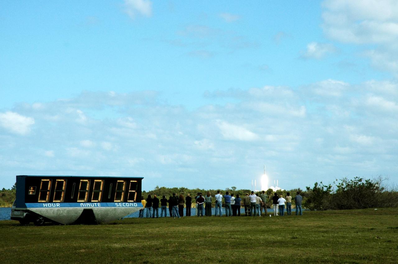KENNEDY SPACE CENTER, FLA. — Spectators and photographers enjoy the view as the NASA New Horizons spacecraft clears the horizon six seconds into the launch (as seen on the countdown clock at left). The spacecraft lifted off on time at 2 p.m. EST aboard an Atlas V rocket from Complex 41 on Cape Canaveral Air Force Station in Florida. This was the third launch attempt in as many days after scrubs due to weather concerns. The compact, 1,050-pound piano-sized probe will get a boost from a kick-stage solid propellant motor for its journey to Pluto. New Horizons will be the fastest spacecraft ever launched, reaching lunar orbit distance in just nine hours and passing Jupiter 13 months later. The New Horizons science payload, developed under direction of Southwest Research Institute, includes imaging infrared and ultraviolet spectrometers, a multi-color camera, a long-range telescopic camera, two particle spectrometers, a space-dust detector and a radio science experiment. The dust counter was designed and built by students at the University of Colorado, Boulder. The launch at this time allows New Horizons to fly past Jupiter in early 2007 and use the planet’s gravity as a slingshot toward Pluto. The Jupiter flyby trims the trip to Pluto by as many as five years and provides opportunities to test the spacecraft’s instruments and flyby capabilities on the Jupiter system. New Horizons could reach the Pluto system as early as mid-2015, conducting a five-month-long study possible only from the close-up vantage of a spacecraft. Photo credit: NASA/Fletch Hildreth