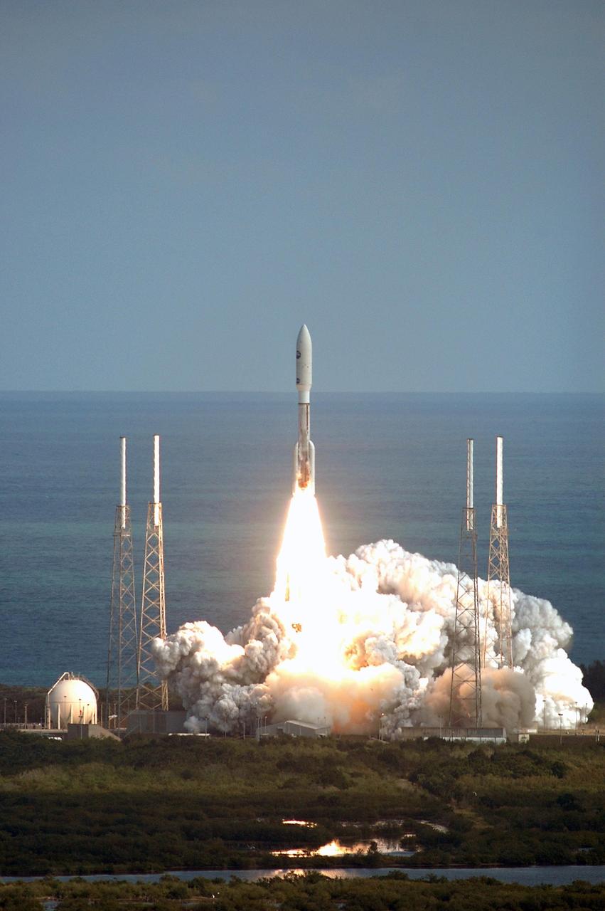 KENNEDY SPACE CENTER, FLA. — Viewed from the top of the Vehicle Assembly Building at Kennedy Space Center, NASA’s New Horizons spacecraft roars off the launch pad aboard an Atlas V rocket spewing flames and smoke. Liftoff was on time at 2 p.m. EST from Complex 41 on Cape Canaveral Air Force Station in Florida. This was the third launch attempt in as many days after scrubs due to weather concerns. The compact, 1,050-pound piano-sized probe will get a boost from a kick-stage solid propellant motor for its journey to Pluto. New Horizons will be the fastest spacecraft ever launched, reaching lunar orbit distance in just nine hours and passing Jupiter 13 months later. The New Horizons science payload, developed under direction of Southwest Research Institute, includes imaging infrared and ultraviolet spectrometers, a multi-color camera, a long-range telescopic camera, two particle spectrometers, a space-dust detector and a radio science experiment. The dust counter was designed and built by students at the University of Colorado, Boulder. The launch at this time allows New Horizons to fly past Jupiter in early 2007 and use the planet’s gravity as a slingshot toward Pluto. The Jupiter flyby trims the trip to Pluto by as many as five years and provides opportunities to test the spacecraft’s instruments and flyby capabilities on the Jupiter system. New Horizons could reach the Pluto system as early as mid-2015, conducting a five-month-long study possible only from the close-up vantage of a spacecraft. Photo credit: NASA/Kim Shiflett