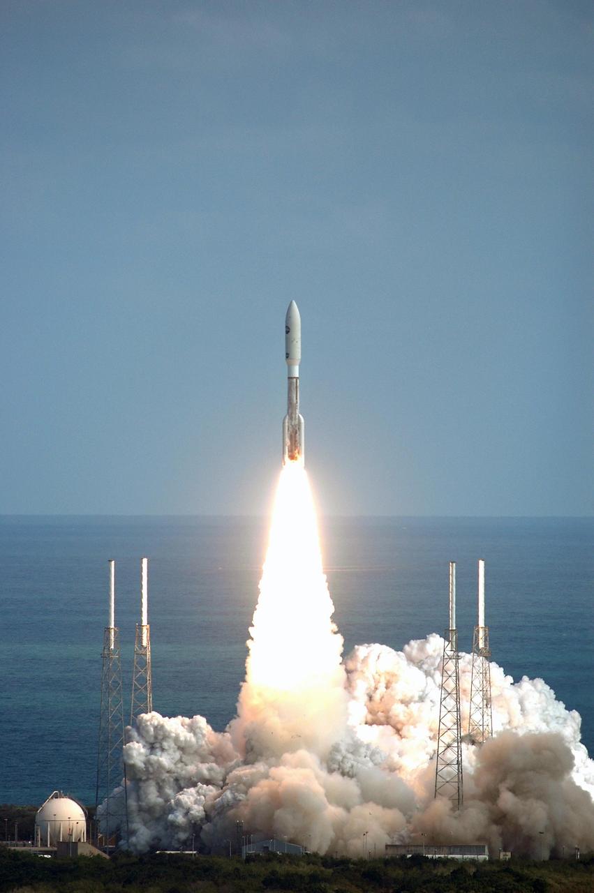 KENNEDY SPACE CENTER, FLA. — Viewed from the top of the Vehicle Assembly Building at Kennedy Space Center, NASA’s New Horizons spacecraft roars off the launch pad aboard an Atlas V rocket spewing flames and smoke. Liftoff was on time at 2 p.m. EST from Complex 41 on Cape Canaveral Air Force Station in Florida. This was the third launch attempt in as many days after scrubs due to weather concerns. The compact, 1,050-pound piano-sized probe will get a boost from a kick-stage solid propellant motor for its journey to Pluto. New Horizons will be the fastest spacecraft ever launched, reaching lunar orbit distance in just nine hours and passing Jupiter 13 months later. The New Horizons science payload, developed under direction of Southwest Research Institute, includes imaging infrared and ultraviolet spectrometers, a multi-color camera, a long-range telescopic camera, two particle spectrometers, a space-dust detector and a radio science experiment. The dust counter was designed and built by students at the University of Colorado, Boulder. The launch at this time allows New Horizons to fly past Jupiter in early 2007 and use the planet’s gravity as a slingshot toward Pluto. The Jupiter flyby trims the trip to Pluto by as many as five years and provides opportunities to test the spacecraft’s instruments and flyby capabilities on the Jupiter system. New Horizons could reach the Pluto system as early as mid-2015, conducting a five-month-long study possible only from the close-up vantage of a spacecraft. Photo credit: NASA/Kim Shiflett