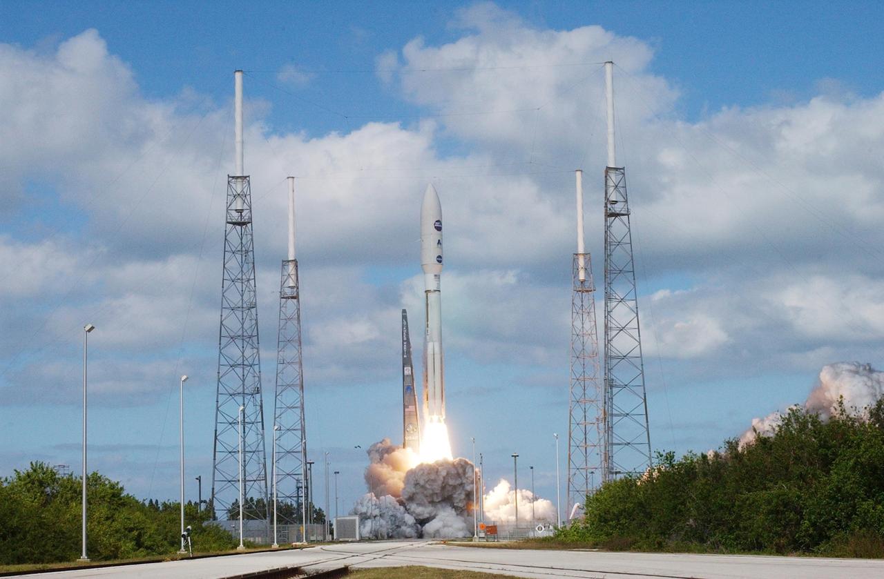 KENNEDY SPACE CENTER, FLA.  —   From among four lightning masts surrounding the launch pad, NASA’s New Horizons spacecraft lifts off the launch pad aboard an Atlas V rocket spewing flames and smoke.  Liftoff was on time at 2 p.m. EST from Complex 41 on Cape Canaveral Air Force Station in Florida.  This was the third launch attempt in as many days after scrubs due to weather concerns.   The compact, 1,050-pound piano-sized probe will get a boost from a kick-stage solid propellant motor for its journey to Pluto. New Horizons will be the fastest spacecraft ever launched, reaching lunar orbit distance in just nine hours and passing Jupiter 13 months later. The New Horizons science payload, developed under direction of Southwest Research Institute, includes imaging infrared and ultraviolet spectrometers, a multi-color camera, a long-range telescopic camera, two particle spectrometers, a space-dust detector and a radio science experiment. The dust counter was designed and built by students at the University of Colorado, Boulder. The launch at this time allows New Horizons to fly past Jupiter in early 2007 and use the planet’s gravity as a slingshot toward Pluto. The Jupiter flyby trims the trip to Pluto by as many as five years and provides opportunities to test the spacecraft’s instruments and flyby capabilities on the Jupiter system. New Horizons could reach the Pluto system as early as mid-2015, conducting a five-month-long study possible only from the close-up vantage of a spacecraft.