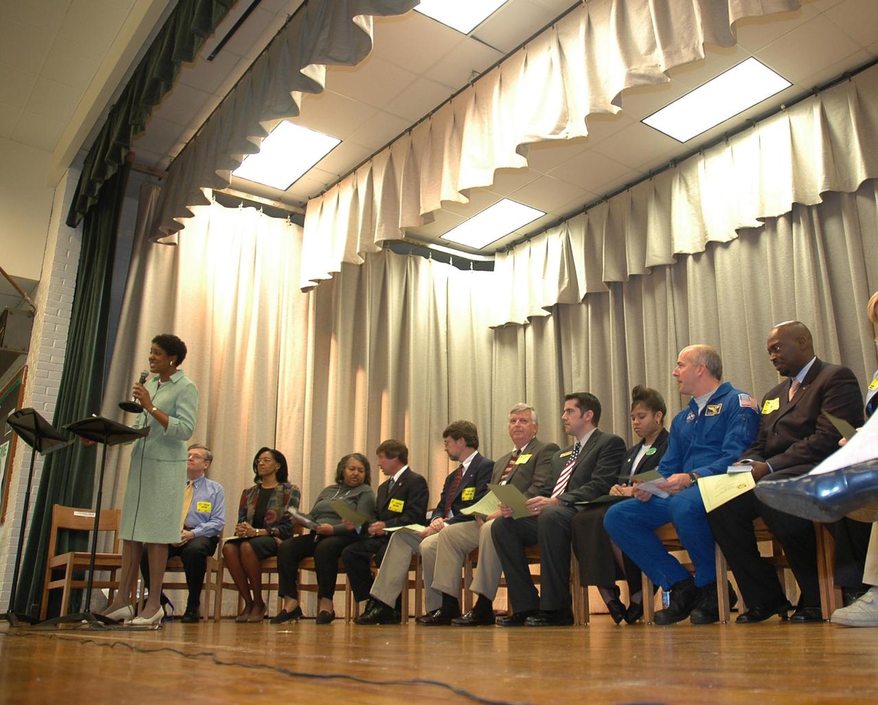 KENNEDY SPACE CENTER, FLA.  —  Christine Nixon, principal of Warrington Middle School in Pensacola, Fla., introduces guests on stage to the audience of students and faculty.  The occasion is the kickoff of the NASA Explorer School (NES) program at the school.  Seated on stage are (from left) Jim Paul, superintendent of Escambia County Schools; a school official; Denise Jamison, the school’s NASA Team facilitator; Les Gold, NASA aerospace specialist; Gregg Buckingham, NASA official; Jim Kennedy, director of Kennedy Space Center; Charles Baire, District representative, representing Congressman Jeff Miller; Letitia Wheeler, student at Warrington Middle School; Alan Poindexter, NASA astronaut; and Clarence Bostic, NES coordinator.  Kennedy is visiting the school to share the vision for space exploration with the next generation.   He is talking with students about our destiny as explorers, NASA’s stepping stone approach to exploring Earth, the moon, Mars and beyond, how space impacts our lives, and how people and machines rely on each other in space.  NES establishes a three-year partnership annually between NASA and 50 NASA Explorer School teams, consisting of teachers and education administrators from diverse communities nationwide.  Photo credit: NASA/Cory Huston