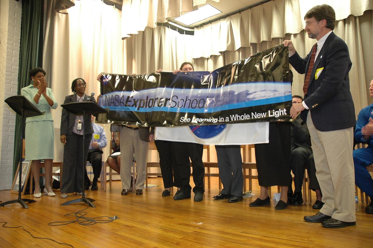 KENNEDY SPACE CENTER, FLA.  — Christine Nixon (left), principal of Warrington Middle School in Pensacola, Fla., is presented a banner recognizing the school’s new partnership with NASA as a NASA Explorer School.  At far right is NASA official Gregg Buckingham, who was joined by Center Director Jim Kennedy and astronaut Alan Poindexter for this kickoff event at the school.   Kennedy is visiting the school to share the vision for space exploration with the next generation.   He is talking with students about our destiny as explorers, NASA’s stepping stone approach to exploring Earth, the moon, Mars and beyond, how space impacts our lives, and how people and machines rely on each other in space.  NES establishes a three-year partnership annually between NASA and 50 NASA Explorer School teams, consisting of teachers and education administrators from diverse communities nationwide.  Photo credit: NASA/Cory Huston
