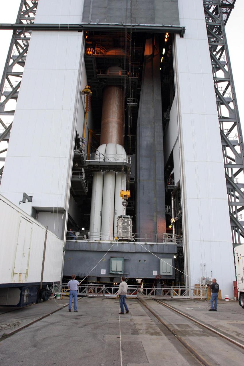 KENNEDY SPACE CENTER, FLA.  — On Complex 41 at Cape Canaveral Air Force Station in Florida, workers on the ground oversee the radioisotope thermoelectric generator (RTG) being lifted into the Vertical Integration Facility.  The RTG will be installed on the New Horizons spacecraft within the fairing at the top of the Atlas V launch vehicle.  Designed and integrated at the Johns Hopkins University Applied Physics Laboratory (APL) in Laurel, Md., New Horizons will launch on a nine-and-a-half-year voyage to Pluto. Typical of RTG-based systems, as on past outer-planet missions, New Horizons does not have a battery for storing power. At the start of the mission, the RTG, which provides power through the natural radioactive decay of plutonium dioxide fuel, will supply approximately 240 watts (at 30 volts of direct current) - the spacecraft’s shunt regulator unit maintains a steady input from the RTG and dissipates power the spacecraft cannot use at a given time. By July 2015 (the earliest Pluto encounter date) that supply decreases to 200 watts at the same voltage, so New Horizons will ease the strain on its limited power source by cycling science instruments during planetary encounters.  On Complex 41 at Cape Canaveral Air Force Station in Florida, workers on the ground oversee the radioisotope thermoelectric generator (RTG) being lifted into the Vertical Integration Facility.  The RTG will be installed on the New Horizons spacecraft within the fairing at the top of the Atlas V launch vehicle.  Designed and integrated at the Johns Hopkins University Applied Physics Laboratory (APL) in Laurel, Md., New Horizons will launch on a nine-and-a-half-year voyage to Pluto. Typical of RTG-based systems, as on past outer-planet missions, New Horizons does not have a battery for storing power. At the start of the mission, the RTG, which provides power through the natural radioactive decay of plutonium dioxide fuel, will supply approximately 240 watts (at 30 volts of direct curren