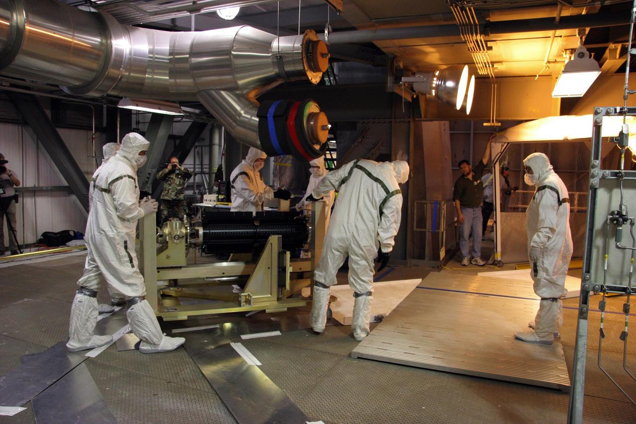 KENNEDY SPACE CENTER, FLA.  — On Complex 41 at Cape Canaveral Air Force Station in Florida, workers move the radioisotope thermoelectric generator (RTG).  The generator will be installed on the New Horizons spacecraft encapsulated inside the fairing.  Designed and integrated at the Johns Hopkins University Applied Physics Laboratory (APL) in Laurel, Md., New Horizons will launch on a nine-and-a-half-year voyage to Pluto. Typical of RTG-based systems, as on past outer-planet missions, New Horizons does not have a battery for storing power. At the start of the mission, the RTG, which provides power through the natural radioactive decay of plutonium dioxide fuel, will supply approximately 240 watts (at 30 volts of direct current) - the spacecraft’s shunt regulator unit maintains a steady input from the RTG and dissipates power the spacecraft cannot use at a given time. By July 2015 (the earliest Pluto encounter date) that supply decreases to 200 watts at the same voltage, so New Horizons will ease the strain on its limited power source by cycling science instruments during planetary encounters.  On Complex 41 at Cape Canaveral Air Force Station in Florida, workers on the ground oversee the radioisotope thermoelectric generator (RTG) being lifted into the Vertical Integration Facility.  The RTG will be installed on the New Horizons spacecraft within the fairing at the top of the Atlas V launch vehicle.  Designed and integrated at the Johns Hopkins University Applied Physics Laboratory (APL) in Laurel, Md., New Horizons will launch on a nine-and-a-half-year voyage to Pluto. Typical of RTG-based systems, as on past outer-planet missions, New Horizons does not have a battery for storing power. At the start of the mission, the RTG, which provides power through the natural radioactive decay of plutonium dioxide fuel, will supply approximately 240 watts (at 30 volts of direct current) - the spacecraft’s shunt regulator unit maintains a steady input from the RTG and diss