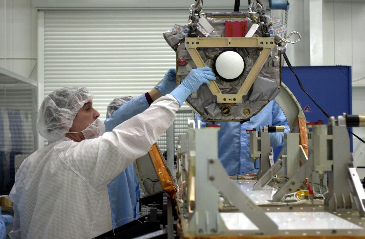 VANDENBERG AIR FORCE BASE, Calif.  —  In the Orbital Sciences Building 836 at Vandenberg Air Force Base in California, workers guide one of three micro-satellites onto a payload support structure.   The three satellites that make up the Space Technology 5 spacecraft, called ST5, will be launched by a Pegasus XL rocket. The satellites  contain miniaturized redundant components and technologies.  Each will validate New Millennium Program selected technologies, such as the Cold Gas Micro-Thruster and X-Band Transponder Communication System.  After deployment from the Pegasus, the micro-satellites will be positioned in a “string of pearls” constellation that demonstrates the ability to position them to perform simultaneous multi-point measurements of the magnetic field using highly sensitive magnetometers.  The data will help scientists understand and map the intensity and direction of the Earth’s magnetic field, its relation to space weather events, and affects on our planet.  With such missions, NASA hopes to improve scientists’ ability to accurately forecast space weather and minimize its harmful effects on space- and ground-based systems.  Launch of ST5 is scheduled for Feb. 28 from Vandenberg Air Force Base.