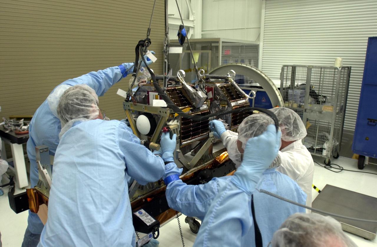 VANDENBERG AIR FORCE BASE, Calif.  —  In the Orbital Sciences Building 836 at Vandenberg Air Force Base in California, workers lower the second satellite onto the payload support structure.  Three micro-satellites are being mounted on a payload support structure.  The three satellites make up the Space Technology 5 spacecraft, called ST5, and will be launched by a Pegasus XL rocket. The satellites contain miniaturized redundant components and technologies.  Each will validate New Millennium Program selected technologies, such as the Cold Gas Micro-Thruster and X-Band Transponder Communication System.  After deployment from the Pegasus, the micro-satellites will be positioned in a “string of pearls” constellation that demonstrates the ability to position them to perform simultaneous multi-point measurements of the magnetic field using highly sensitive magnetometers.  The data will help scientists understand and map the intensity and direction of the Earth’s magnetic field, its relation to space weather events, and affects on our planet.  With such missions, NASA hopes to improve scientists’ ability to accurately forecast space weather and minimize its harmful effects on space- and ground-based systems.  Launch of ST5 is scheduled for Feb. 28 from Vandenberg Air Force Base.